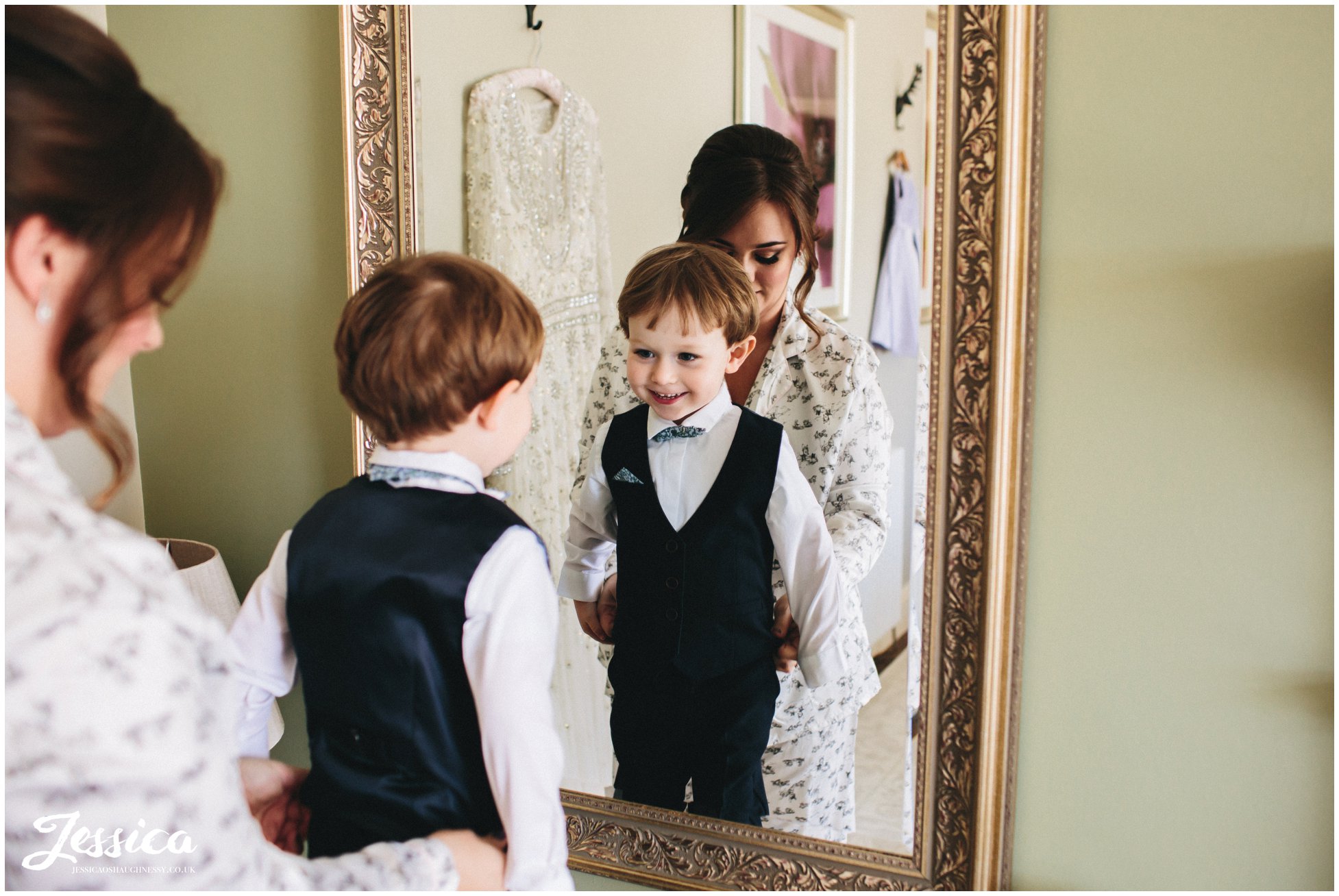 boy looks in mirror wearing his wedding outfit
