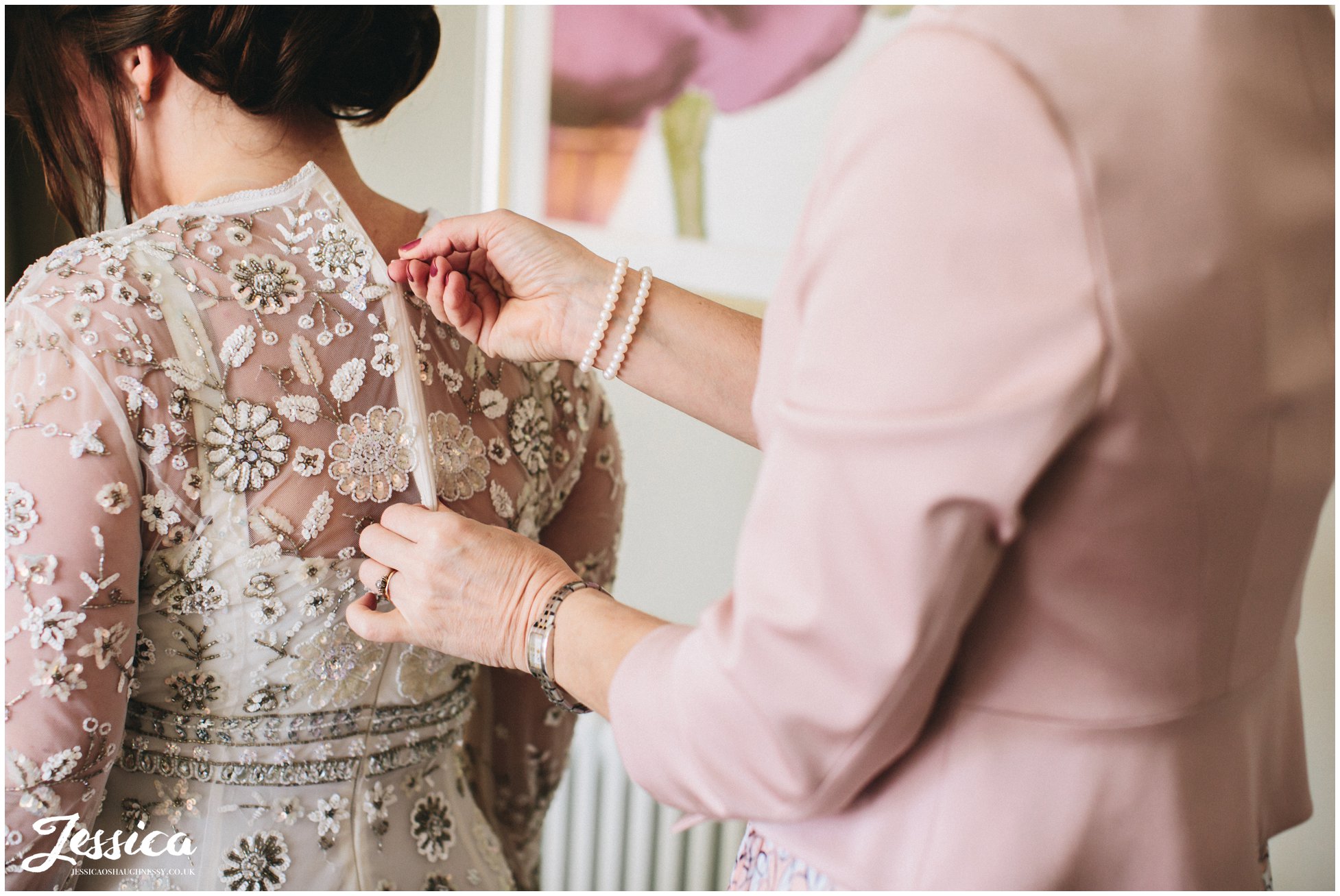 mother of the bride helping bride into her wedding dress