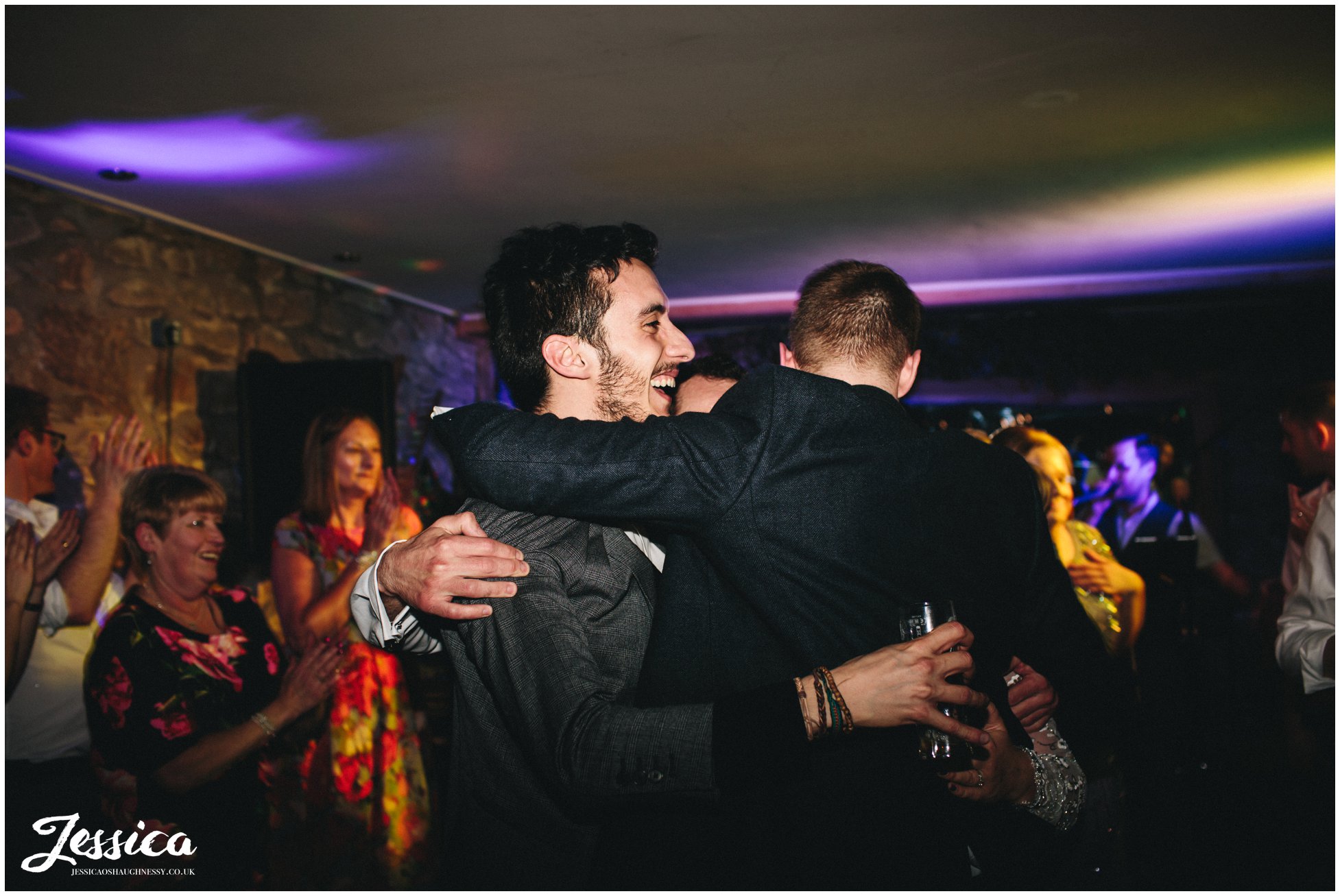 guest hugs the groom on the dancefloor at tower hill barns in wrexham