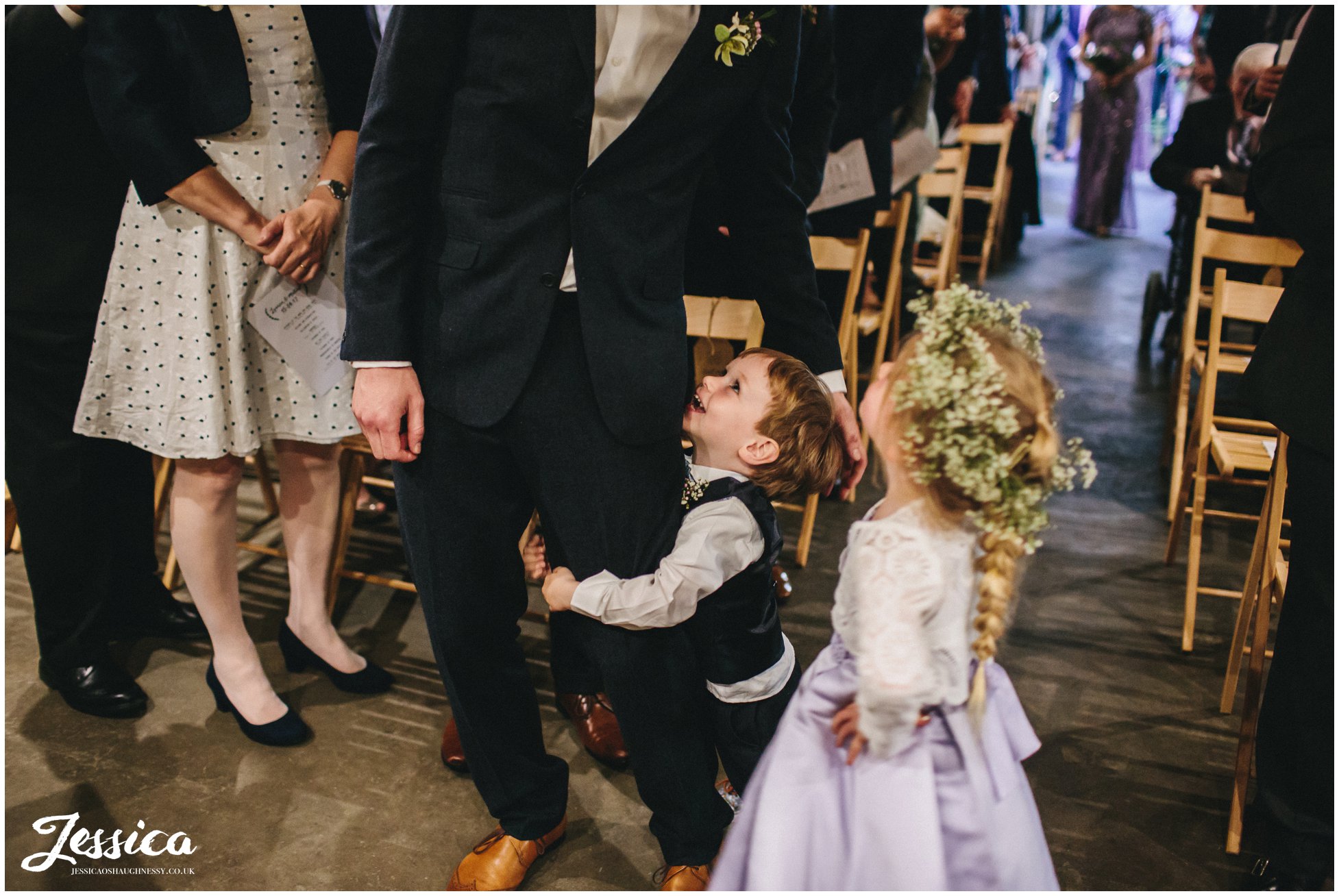 child hugs his dads legs after walking down the aisle