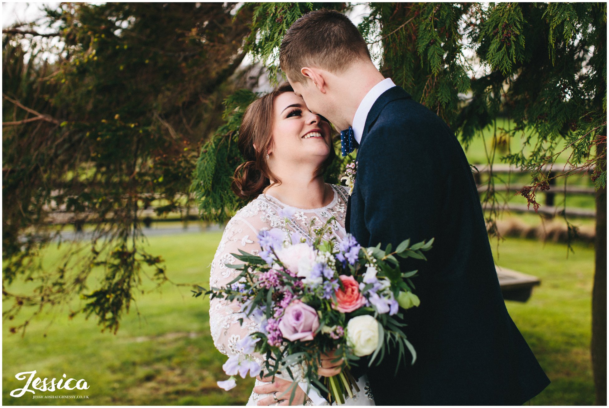 newly wed's kissing next to fur trees