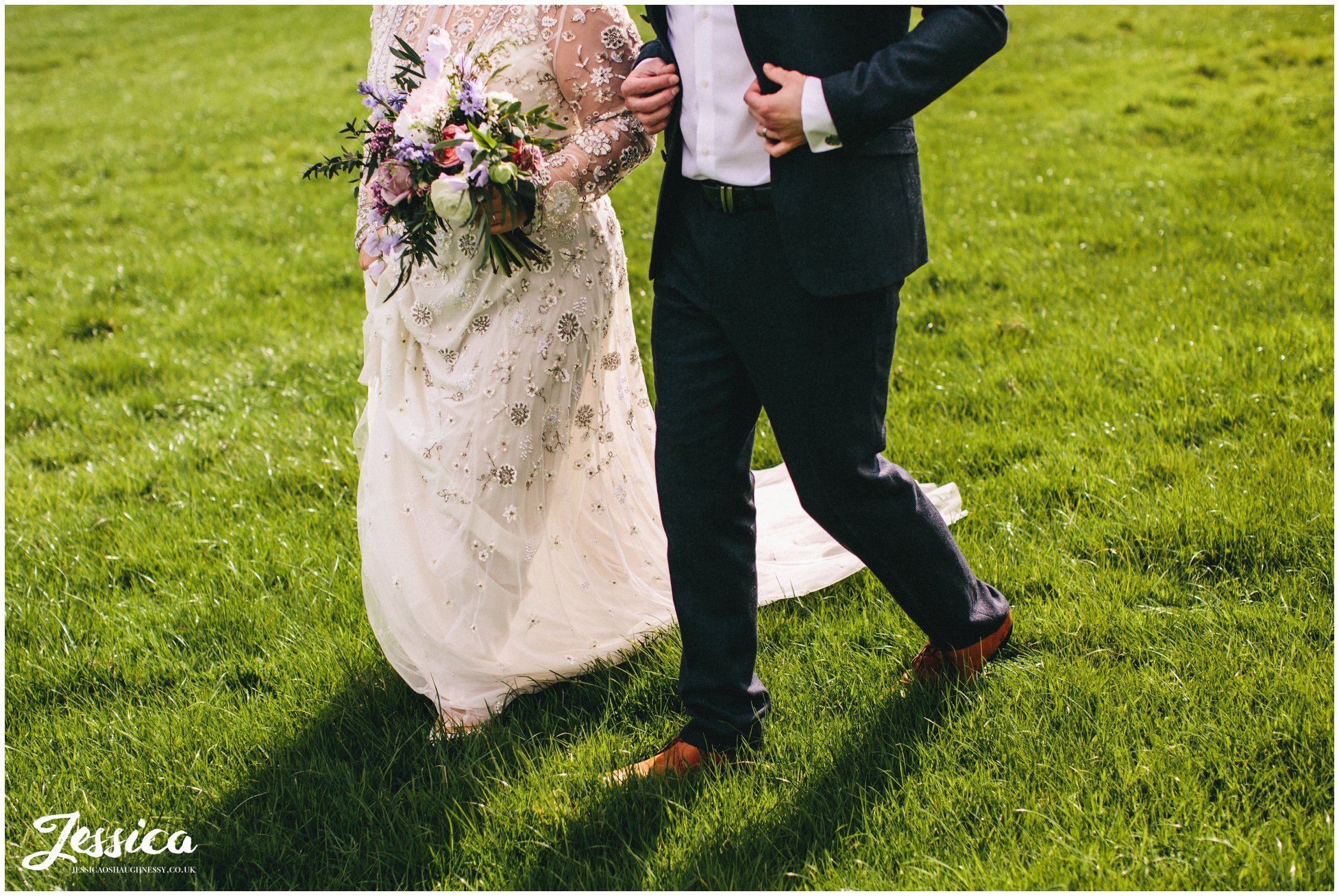 cropped photo of bride & groom walking through the field overlooking tower hill barns