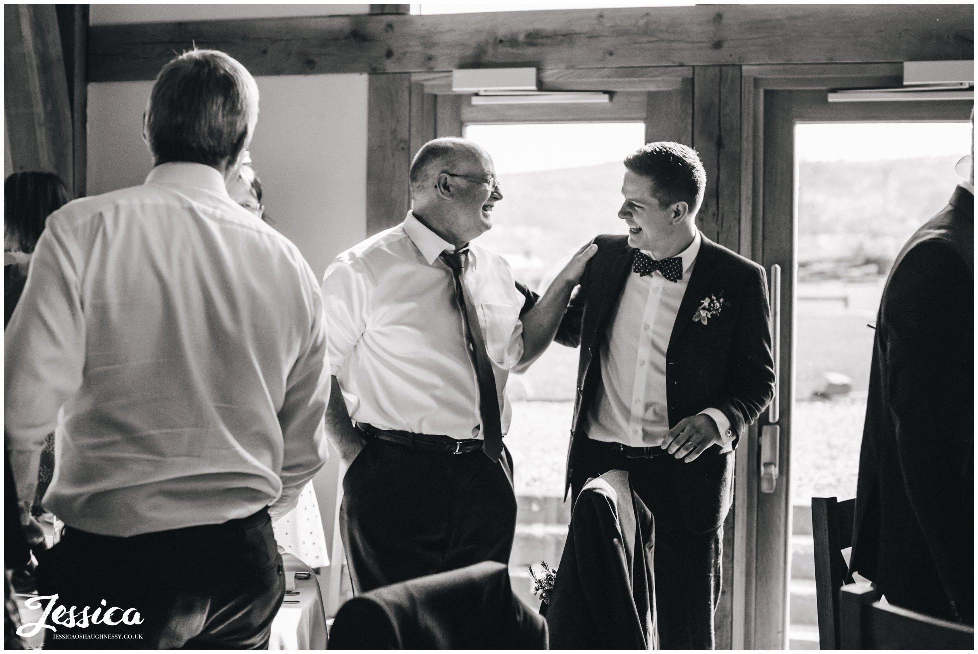 groom & his father laughing in the new barn, north wales