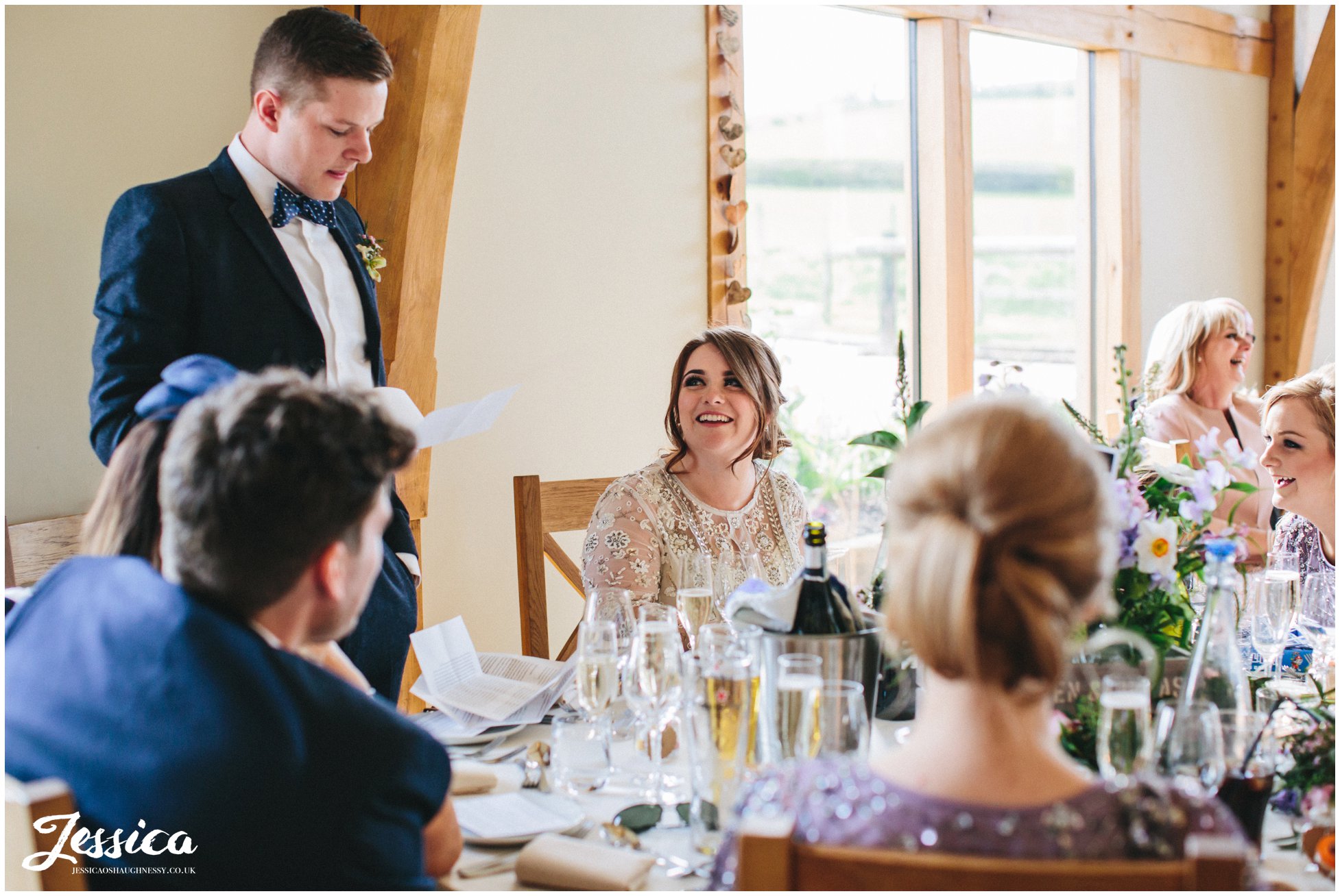 bride smiles at groom during his speech