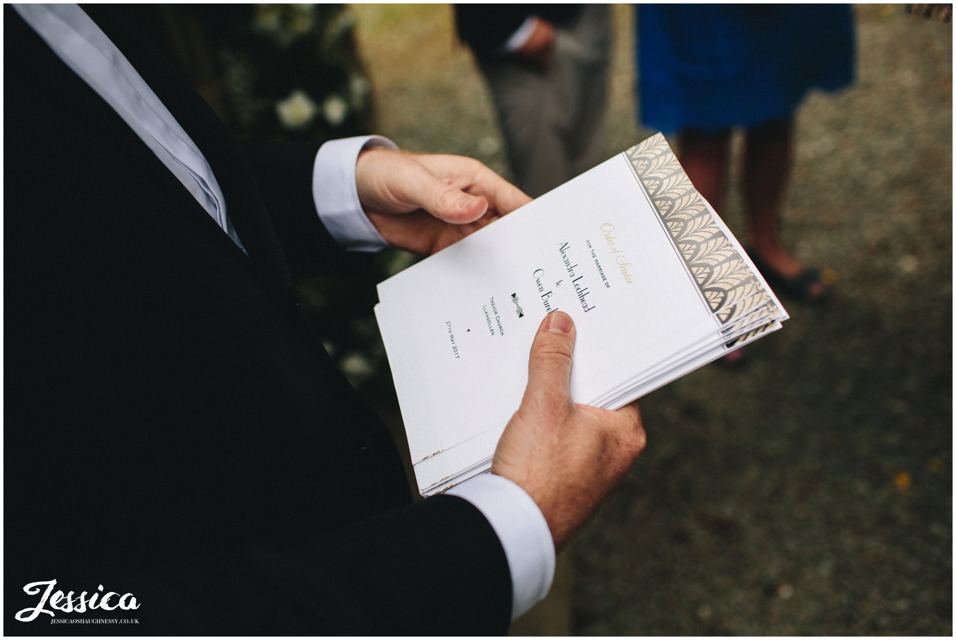 groomsman hands out order of service to wedding guests
