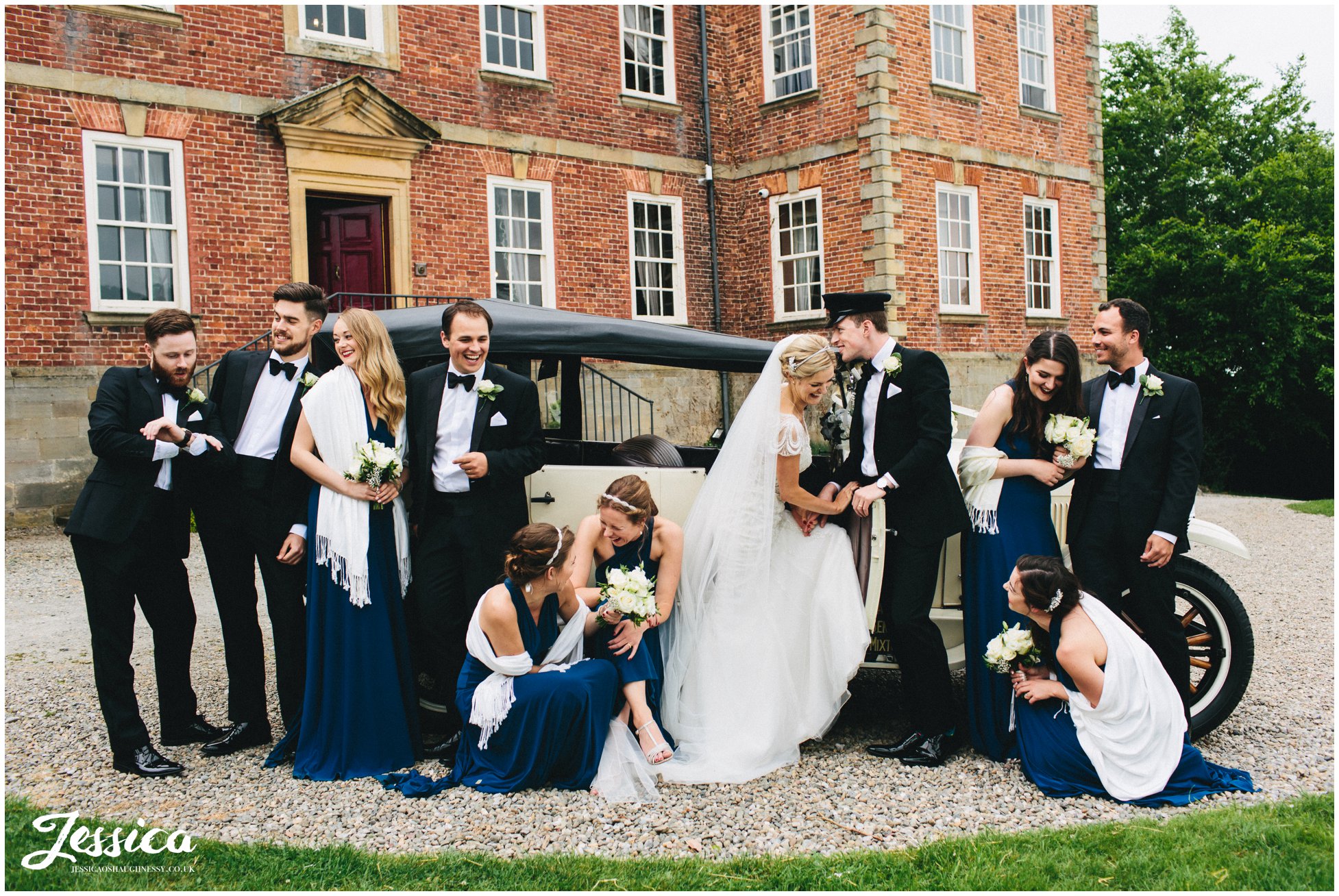 whole wedding party posing in from of the wedding car in north wales