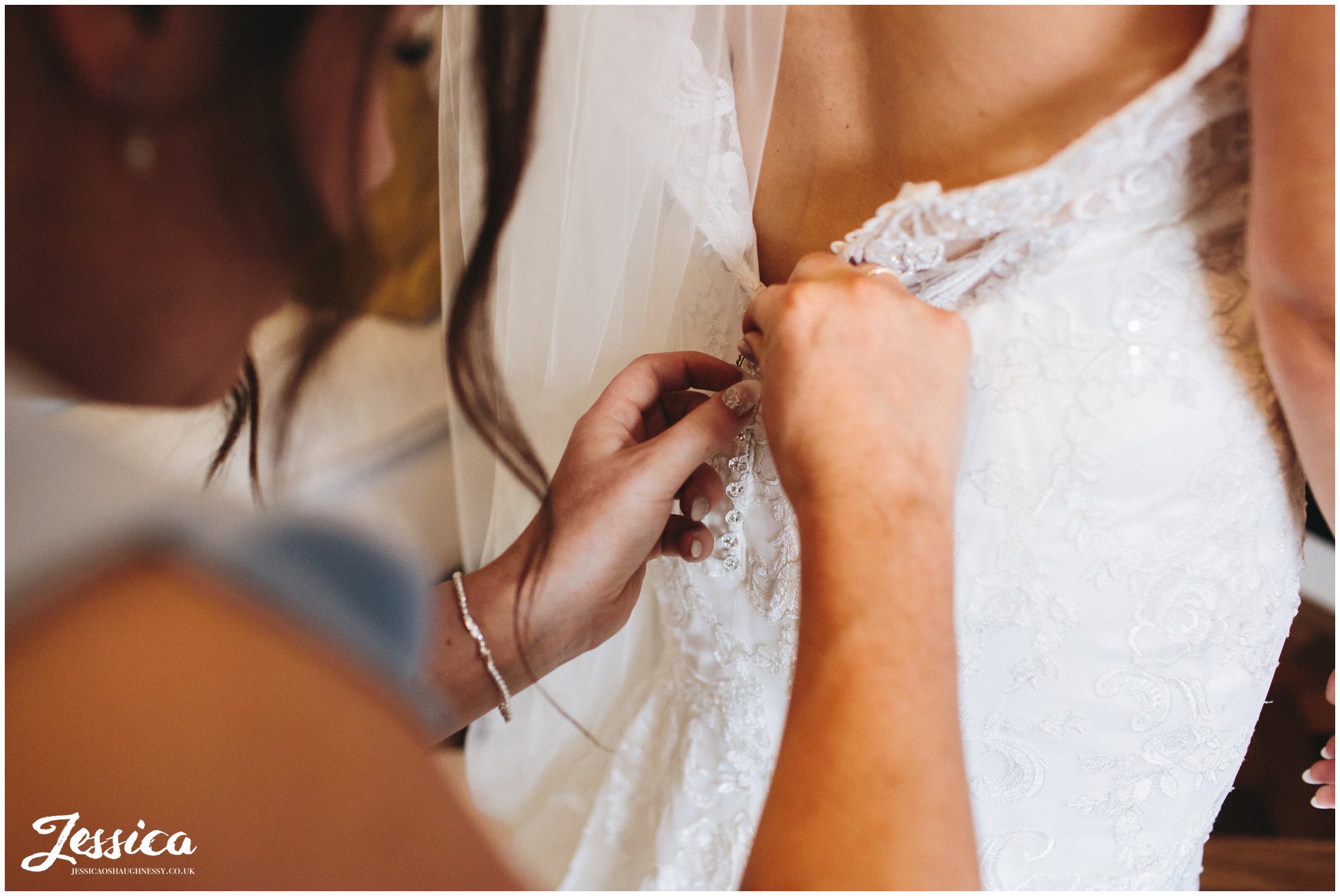 close up of bridesmaid buttoning the wedding dress