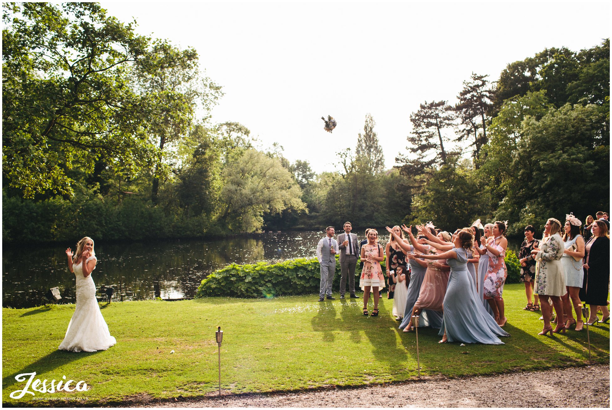 bride throws her bouquet by the lake - wirral wedding photography