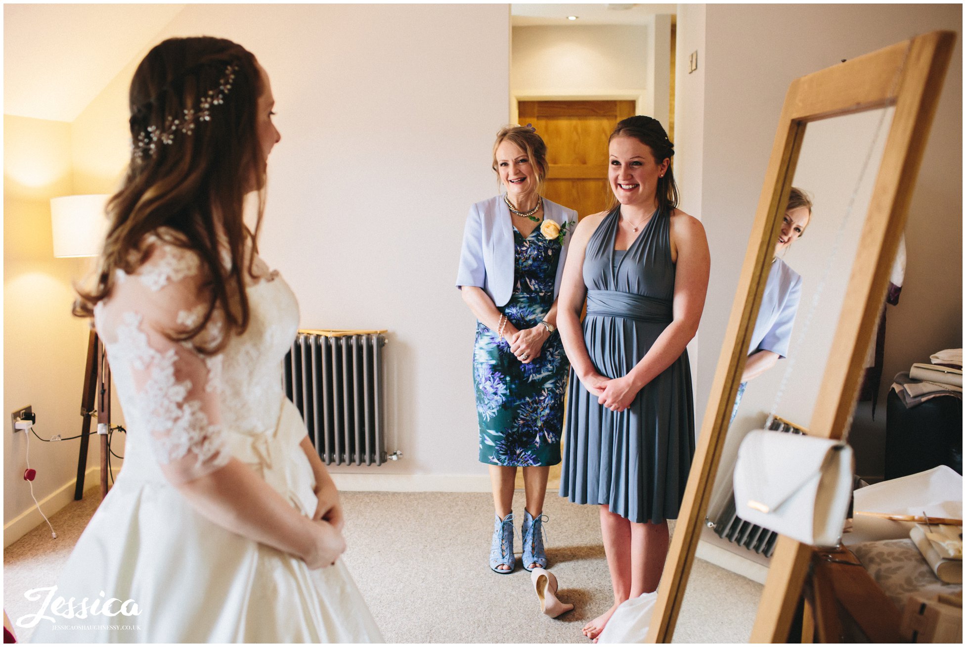 mother and sister of the bride admire her in her wedding dress