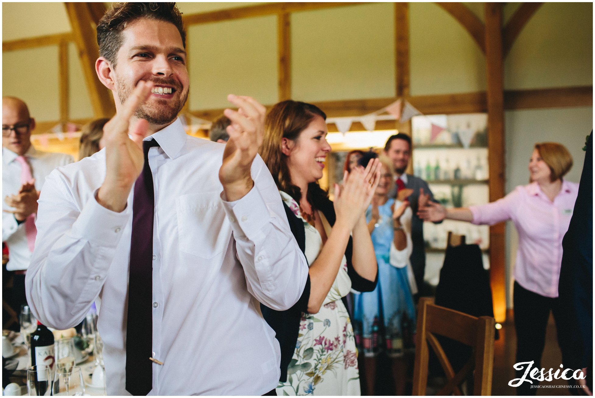 guests aplaude newly wed's as they enter the barn