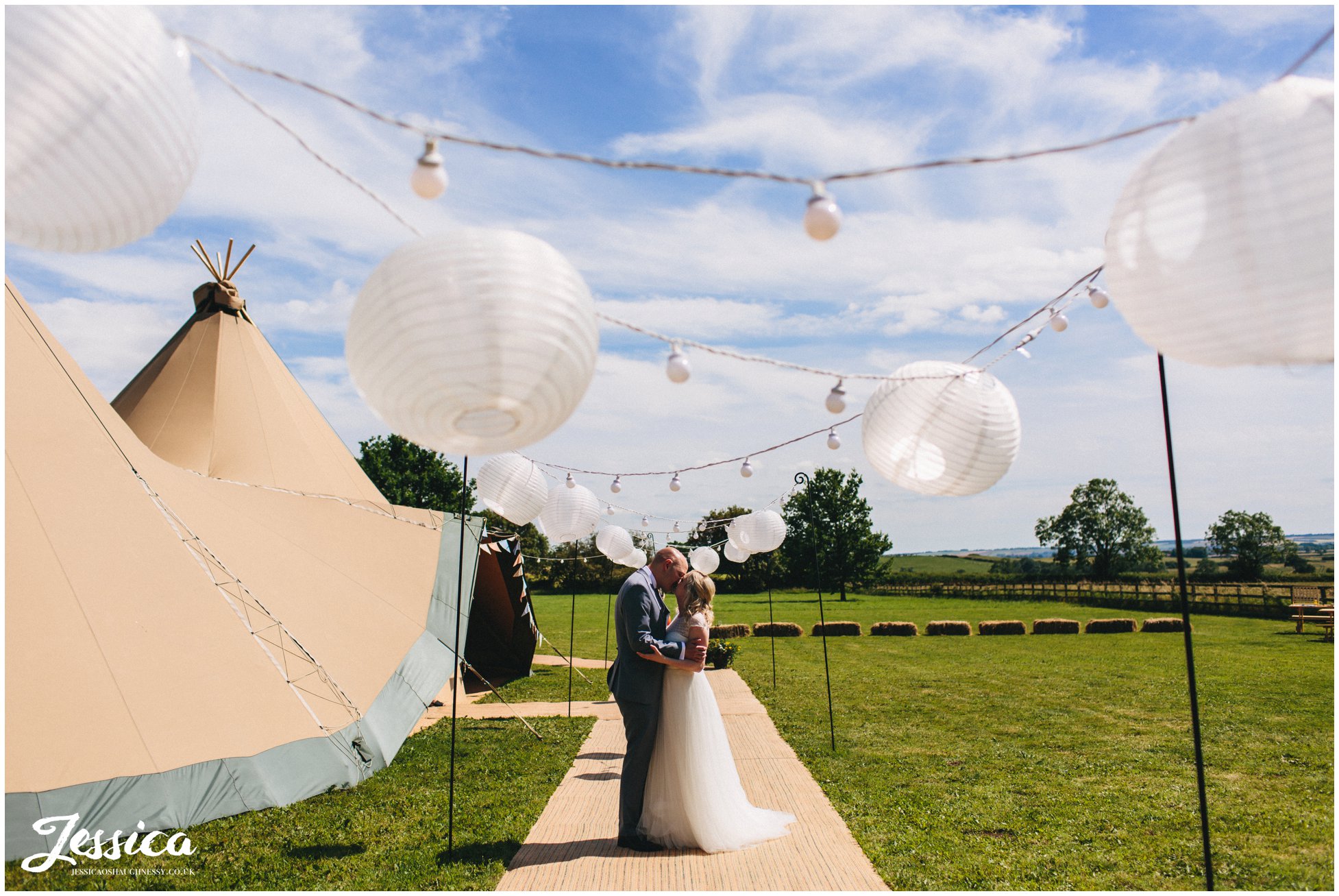 bride and groom kiss under paper lanterns - tipi wedding photography