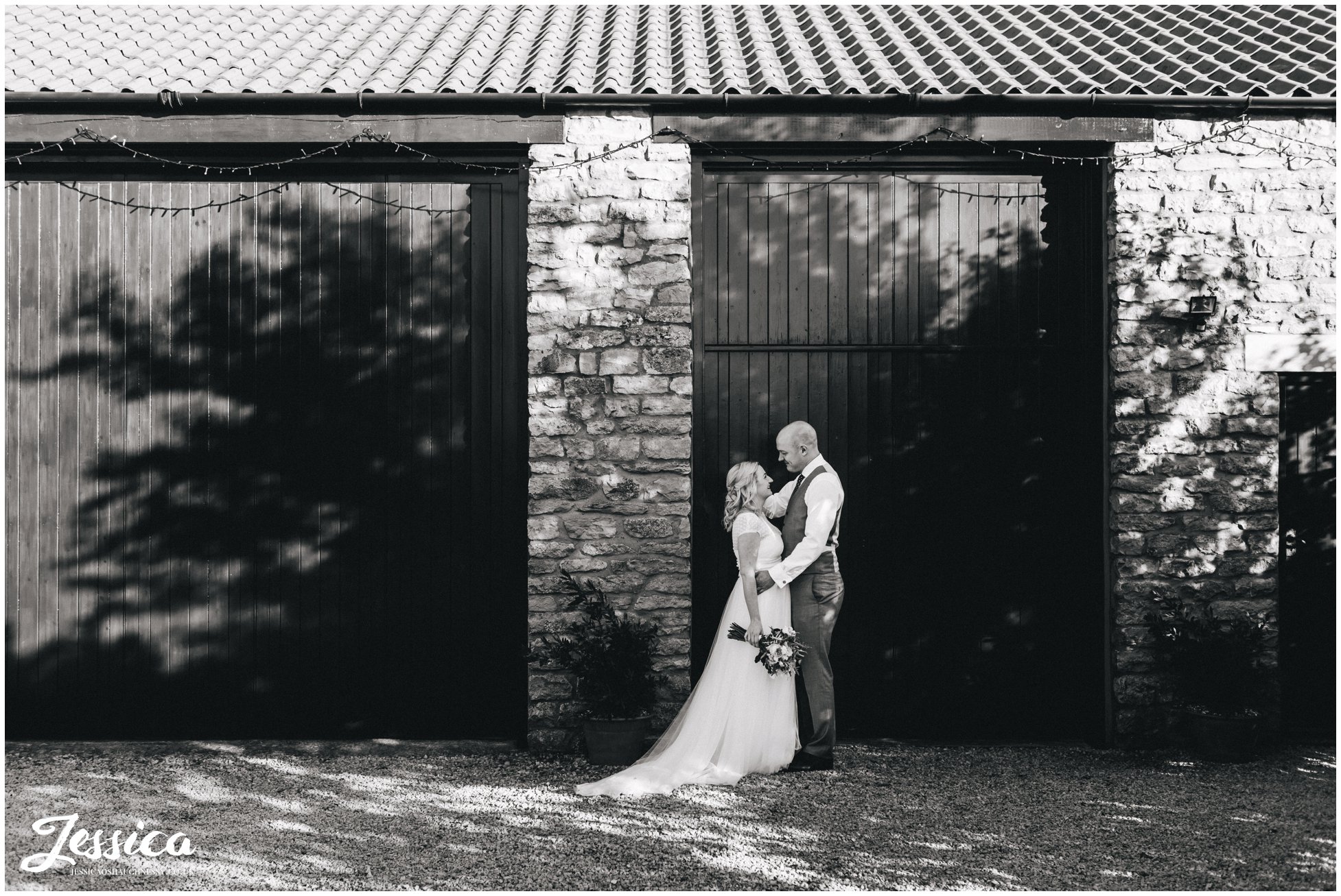 black and white photograph of bride and groom in front of barn doors