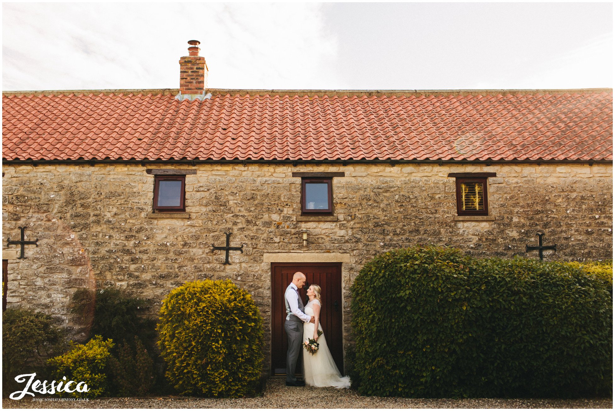 newly wed's stand in doorway in the sunshine