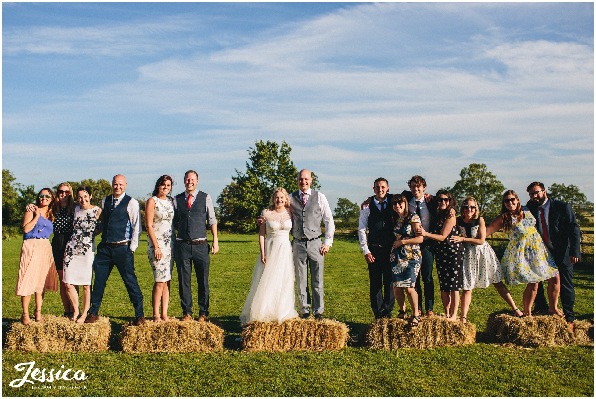 bride, groom and friends pose on hay bails - yorkshire wedding