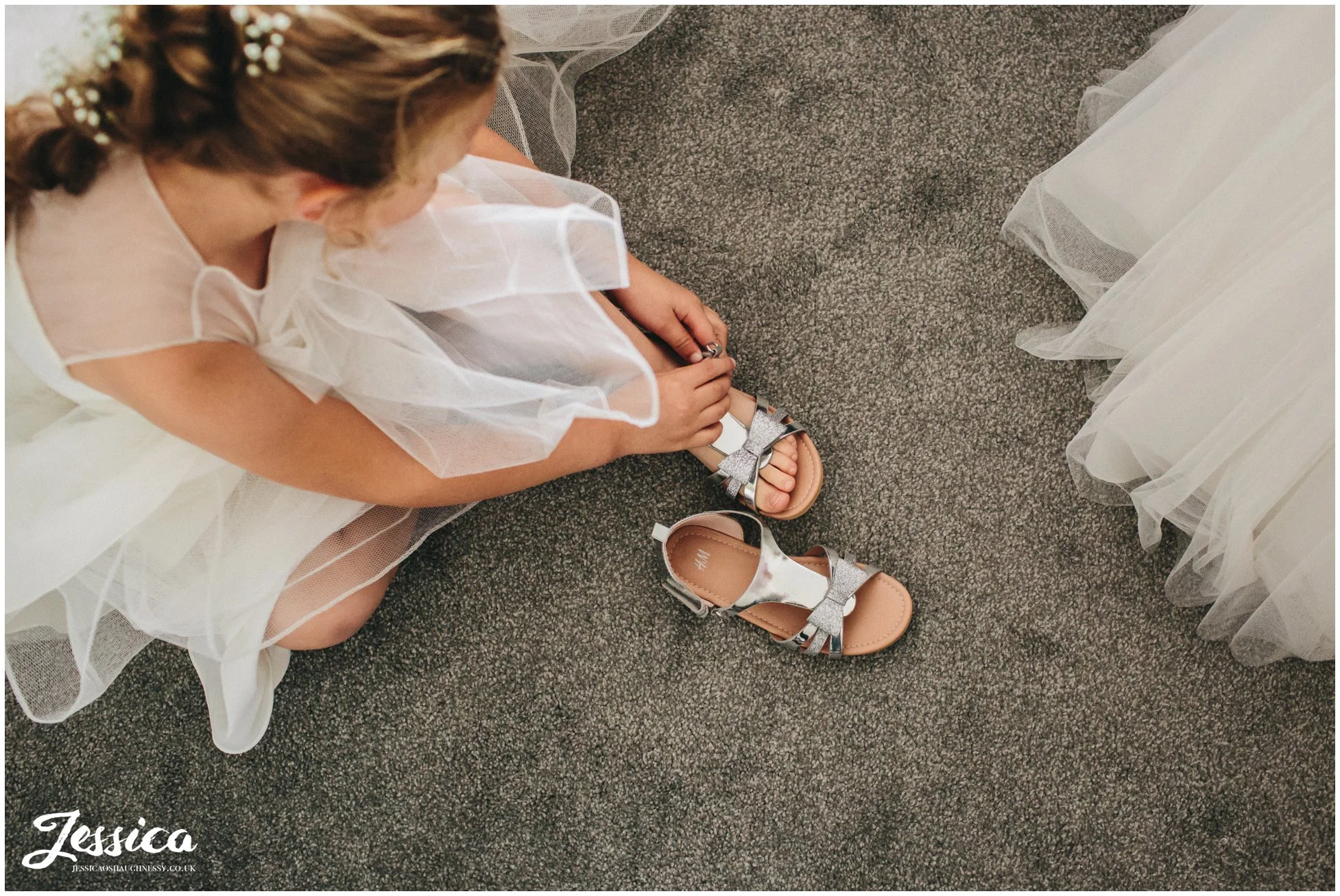 flower girl puts on her shoes - sheldrakes wedding photography