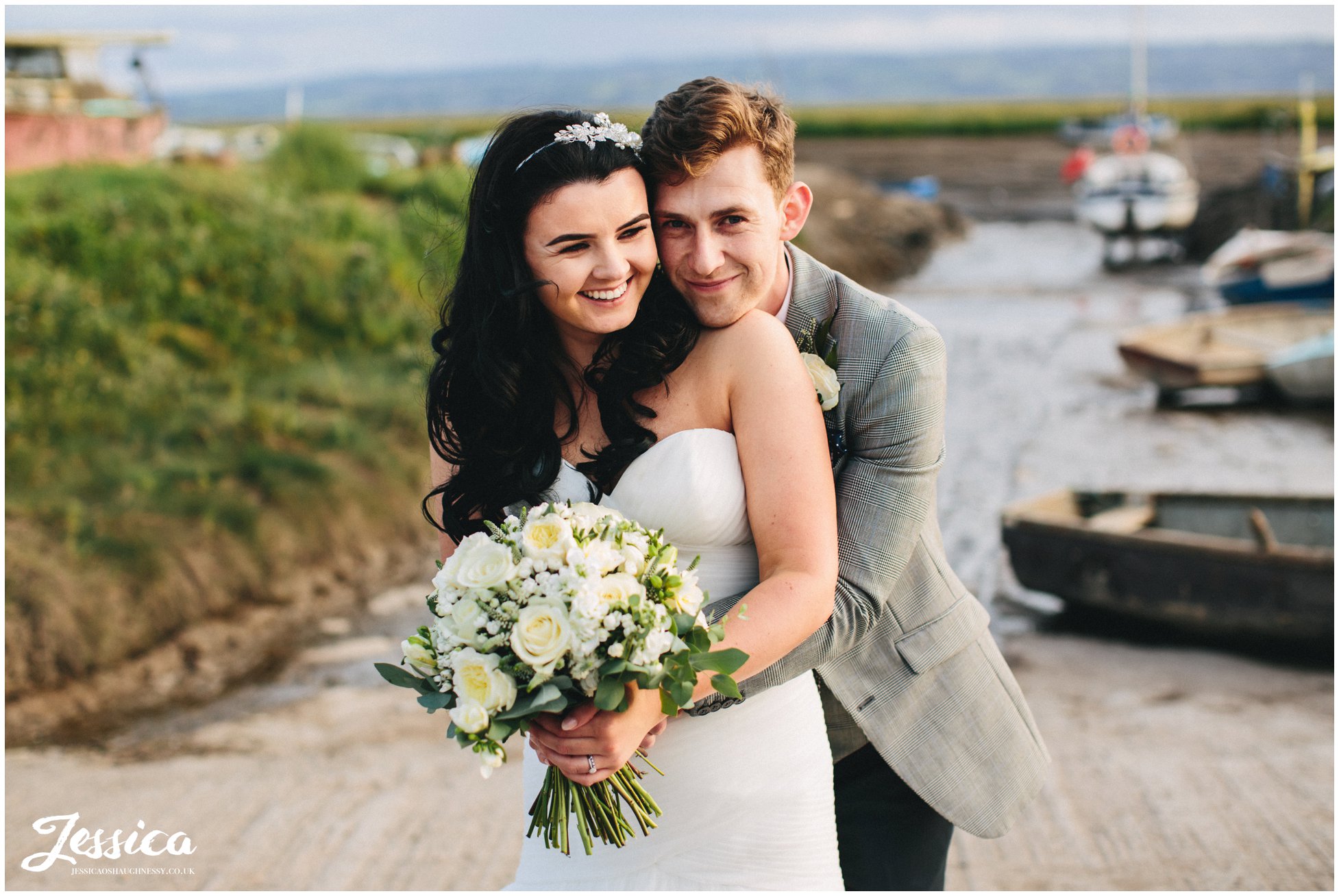 bride & groom embrace in front of the waterfront at sheldrakes restaurant 