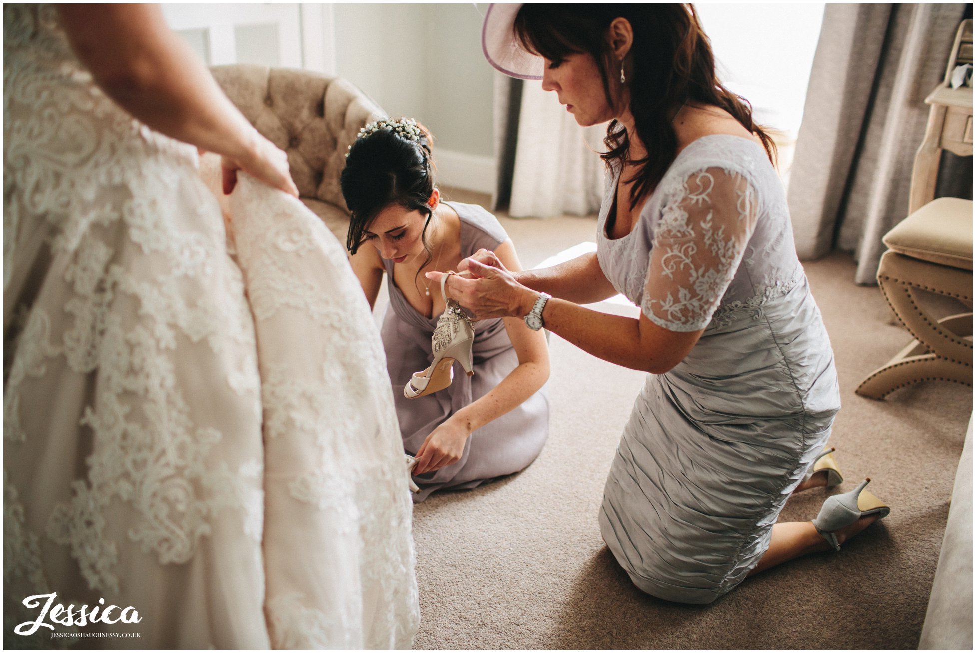 mother of the bride putting the brides shoes on