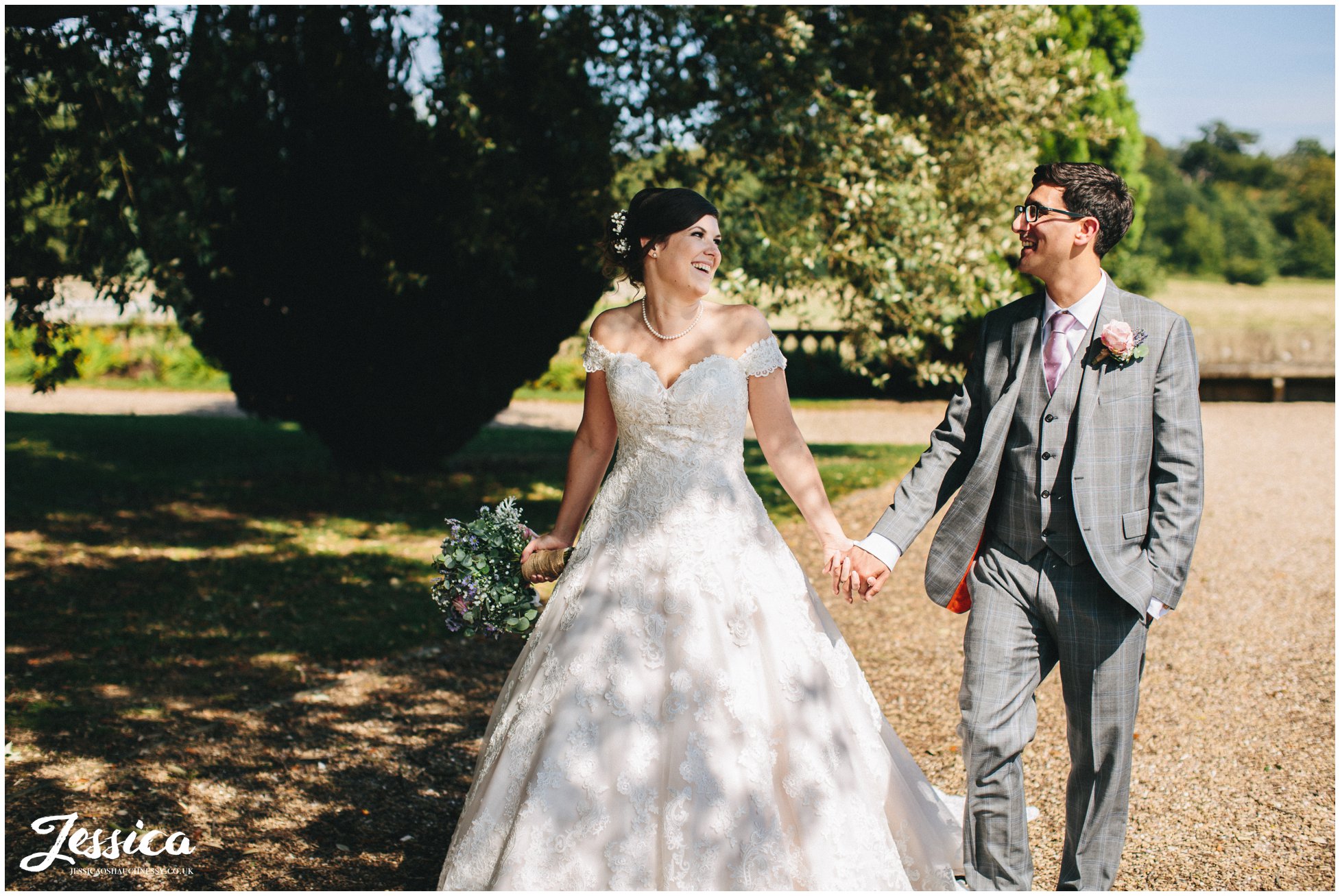 newly wed's walk hand in hand under tree's - prestwold hall wedding