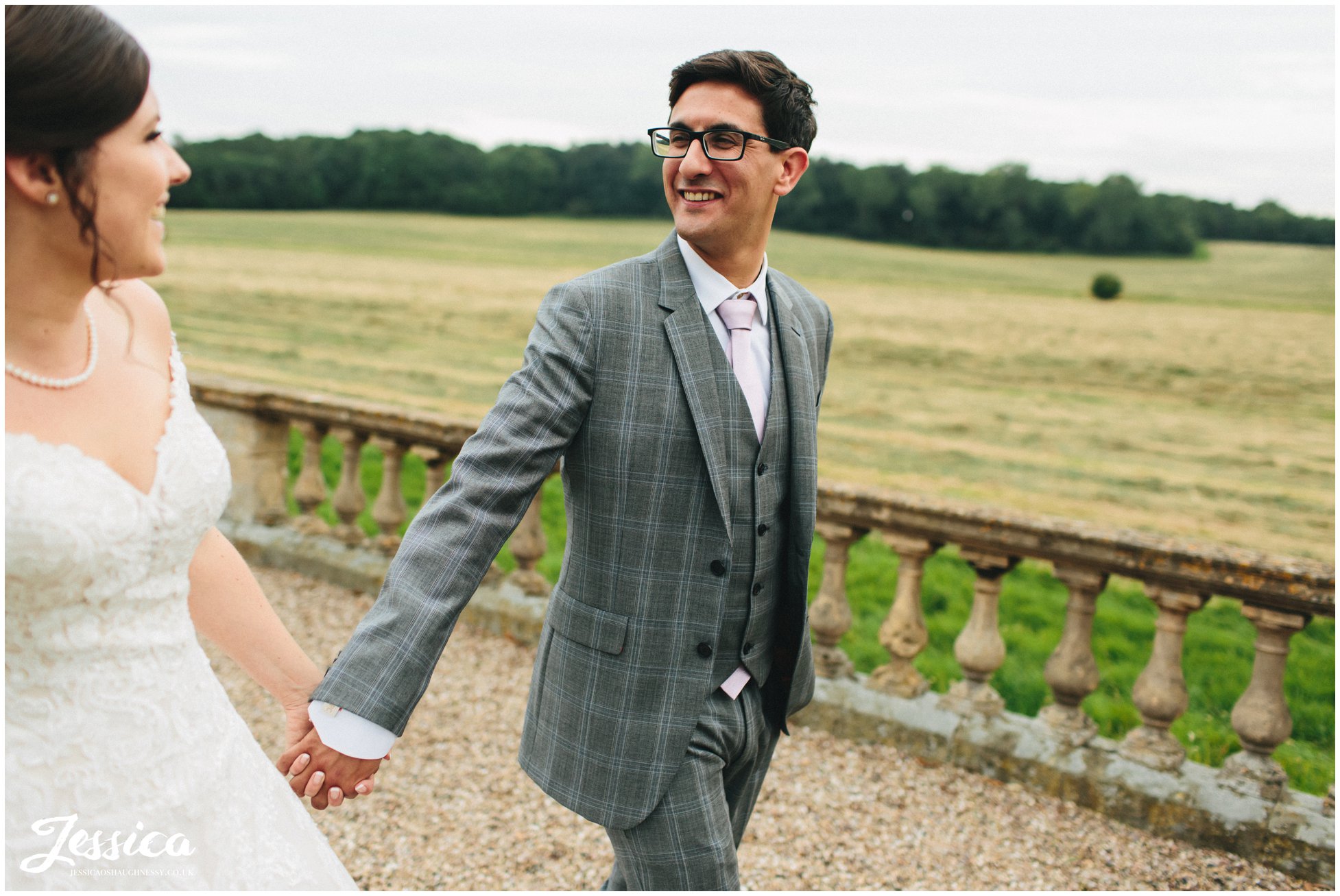 groom holds brides hands in prestwold halls grounds