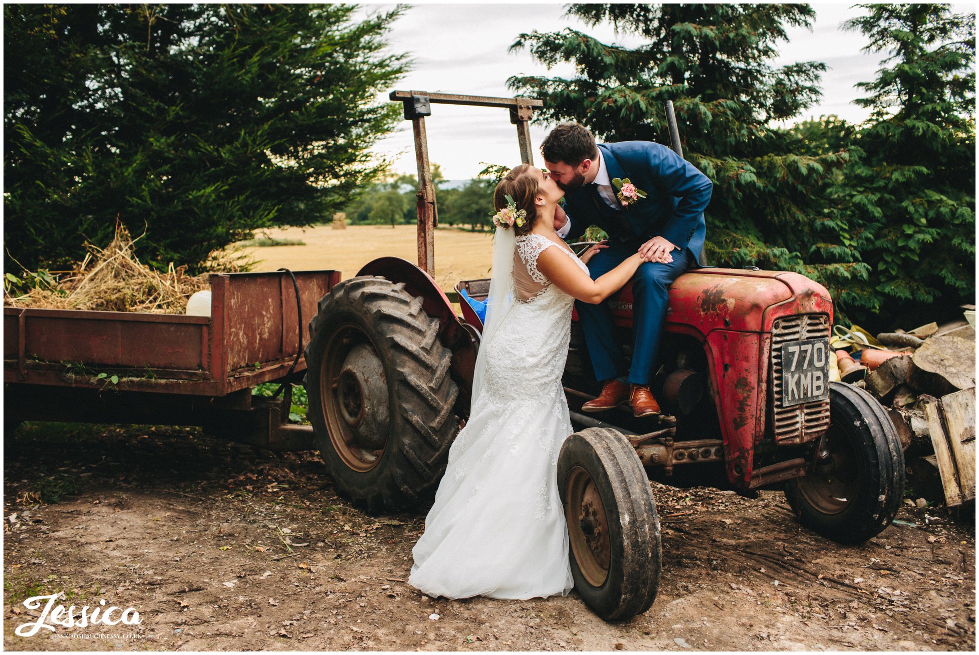 groom kisses bride whilst sat on a tractor at willington hall