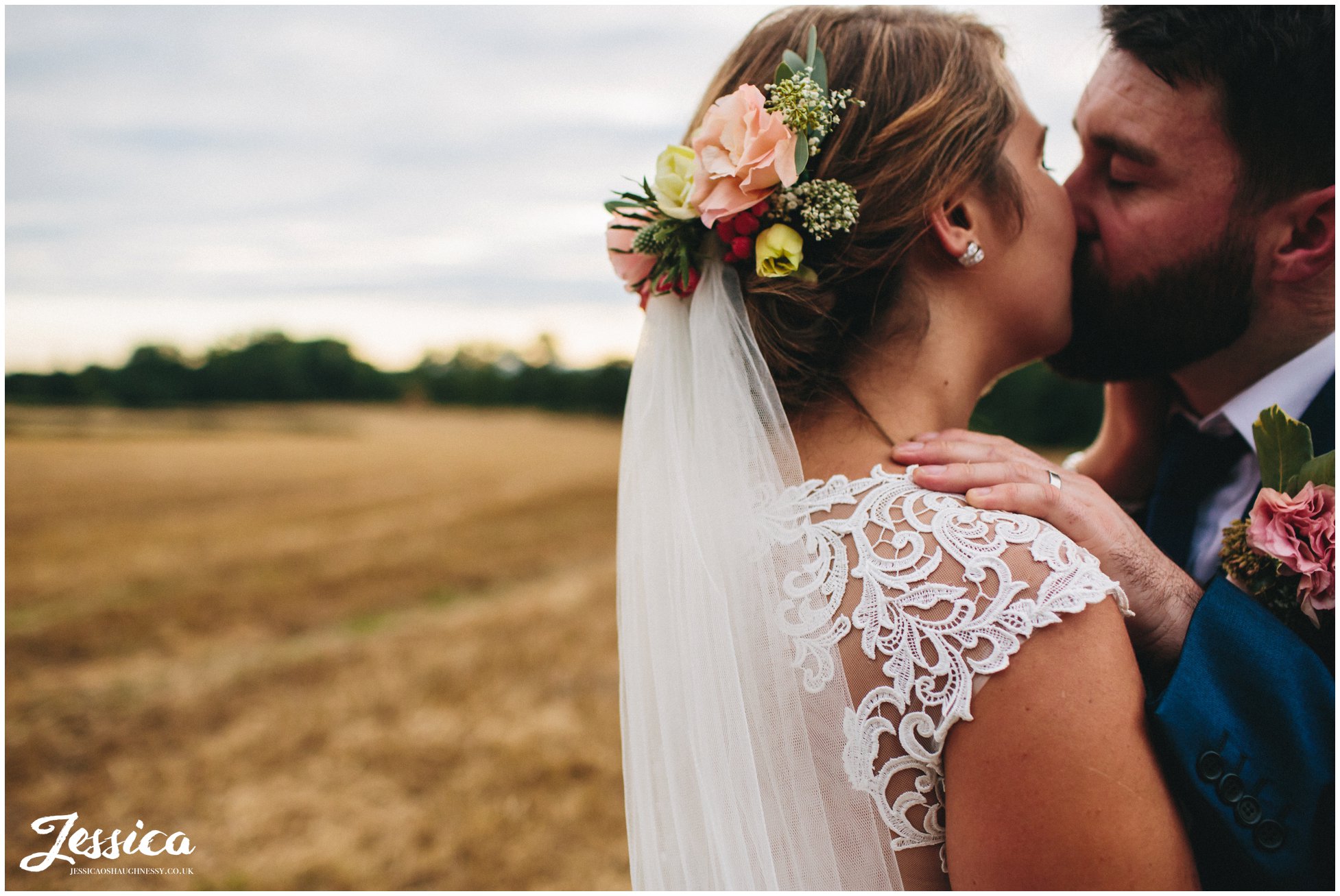 couple kissing as bride wears floral headpiece