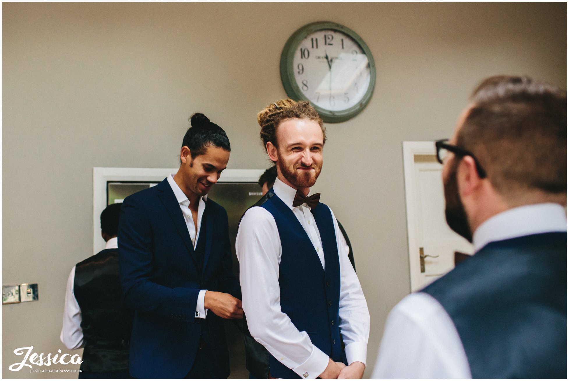 groom helps best man into his waistcoat