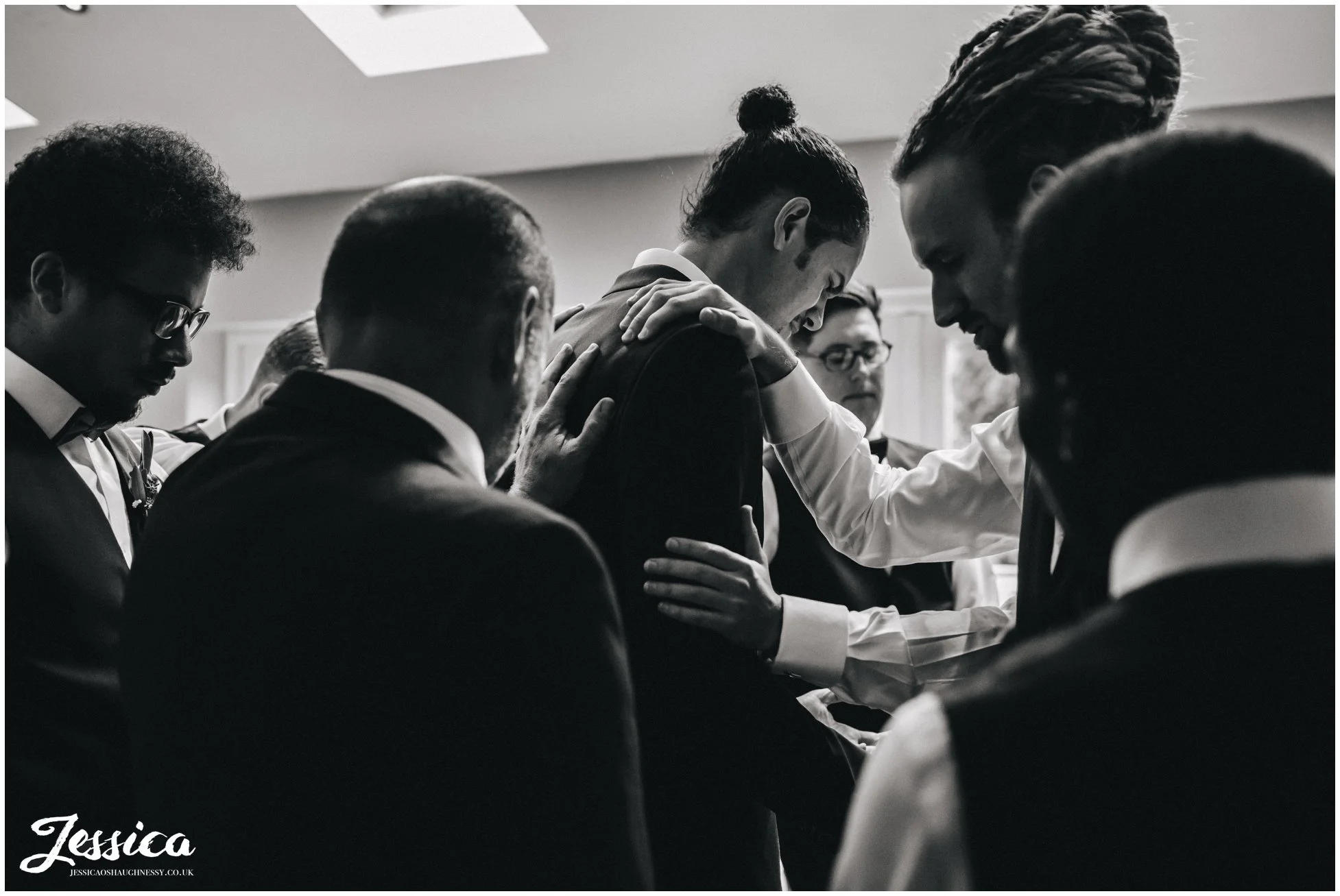 groomsmen gather round groom to pray for the couple before the ceremony
