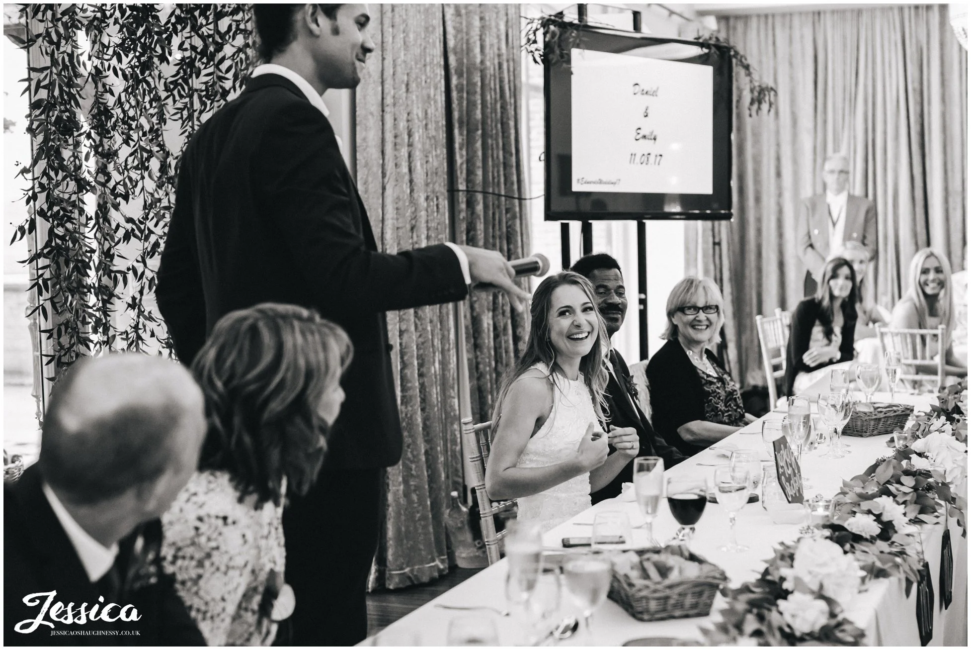 groom gives his speech as bride laughs