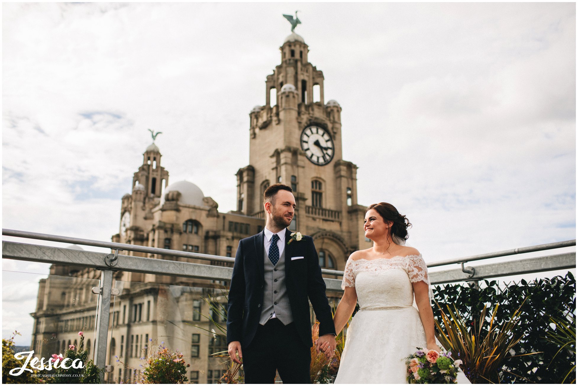 newly wed's holding hands in front of the liver building, liverpool