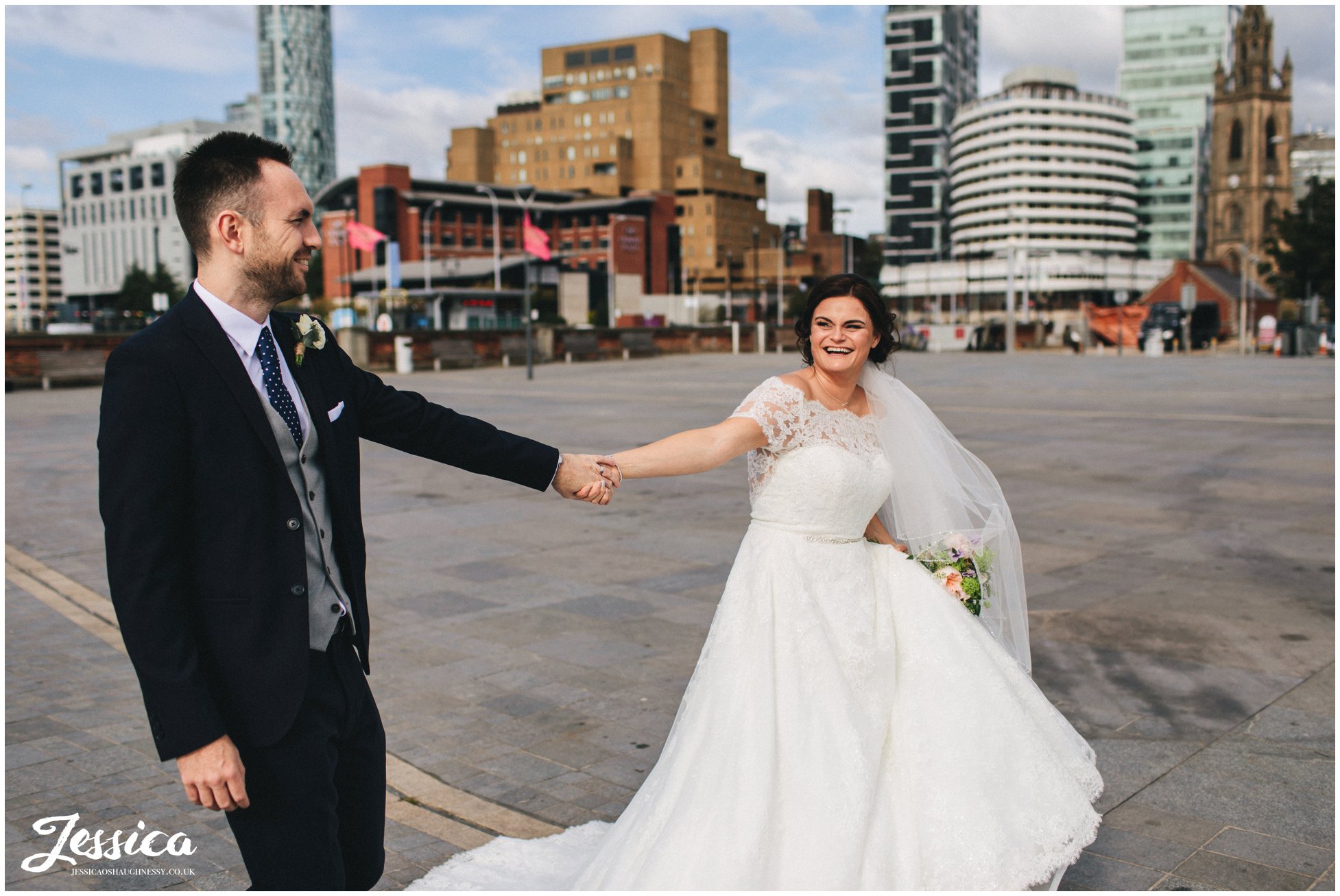 couple walk holding hands along the waterfront in liverpool