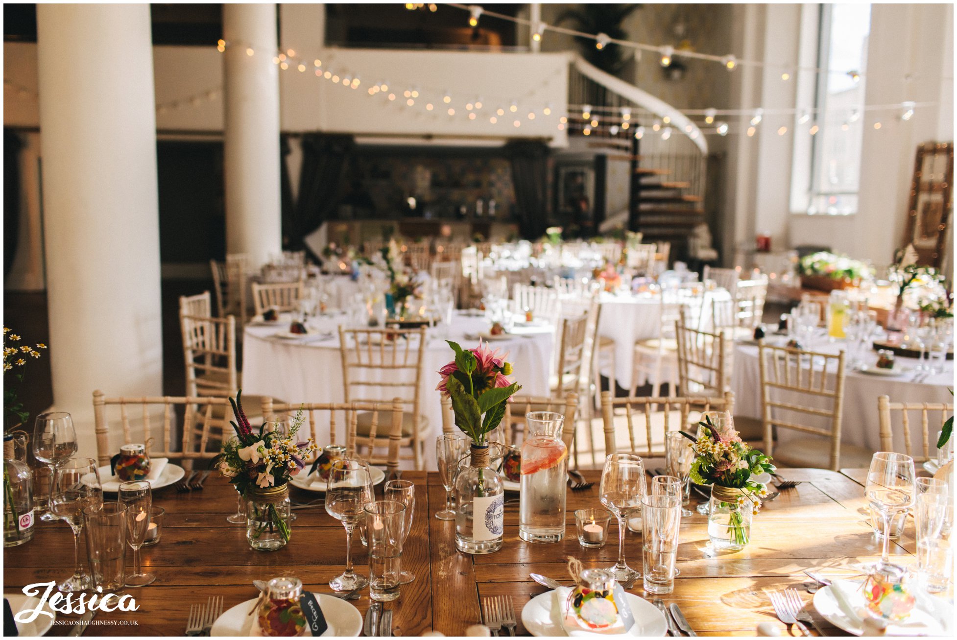 flowers in gin bottles decorate the tables at oh me oh my - a liverpool wedding venue