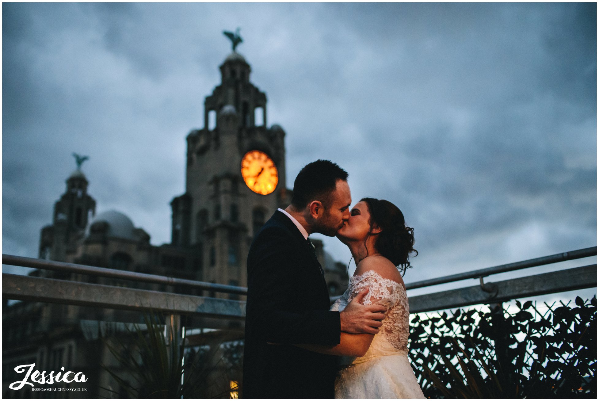 newly wed's kiss in front of liver building at night - oh me oh my rooftop