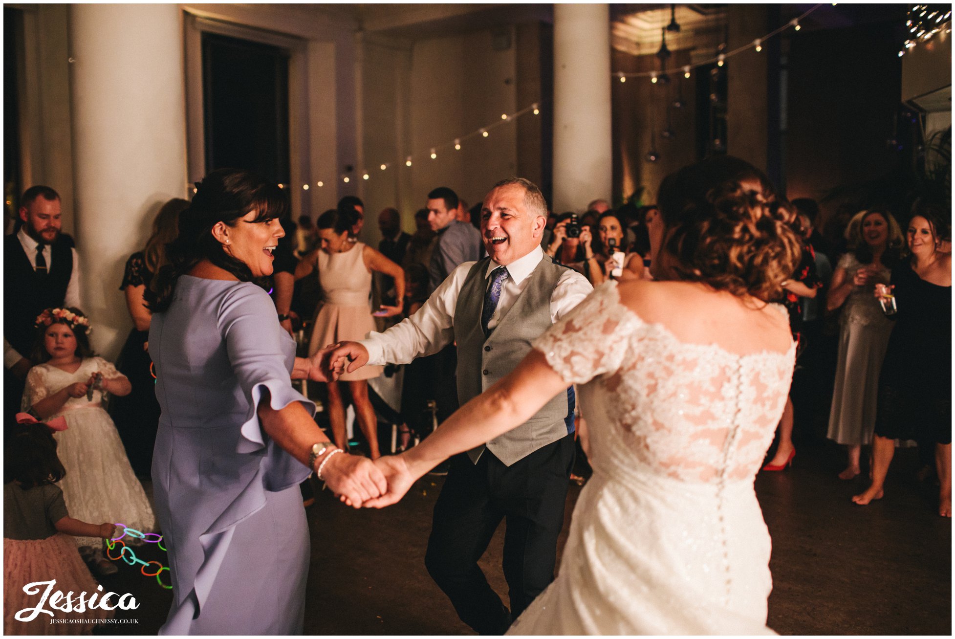 bride dances with mum and dad during her wedding reception