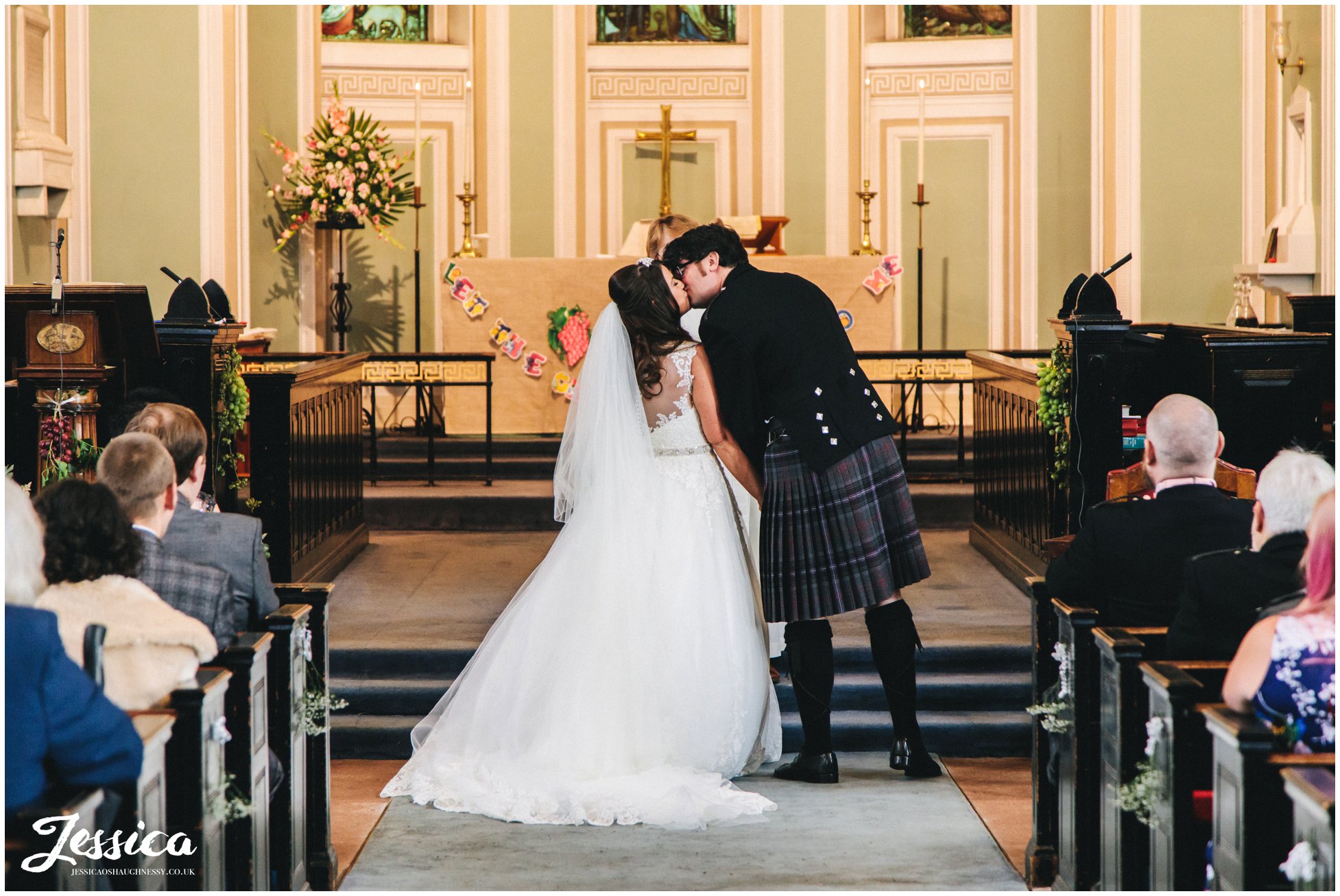 bride and groom share first kiss at the church alter