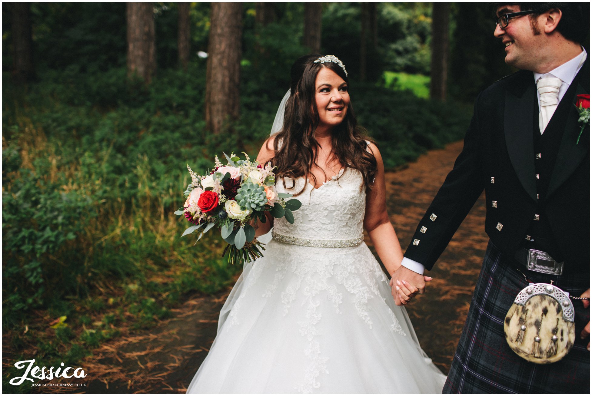 bride and groom walk through woodland at sefton park in liverpool