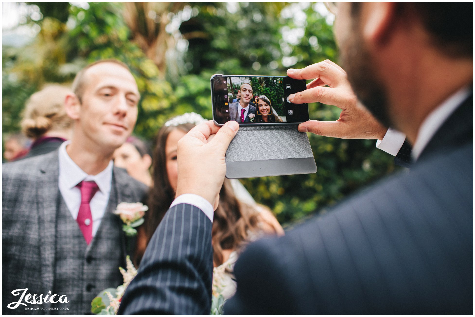wedding guests takes photograph on his phone