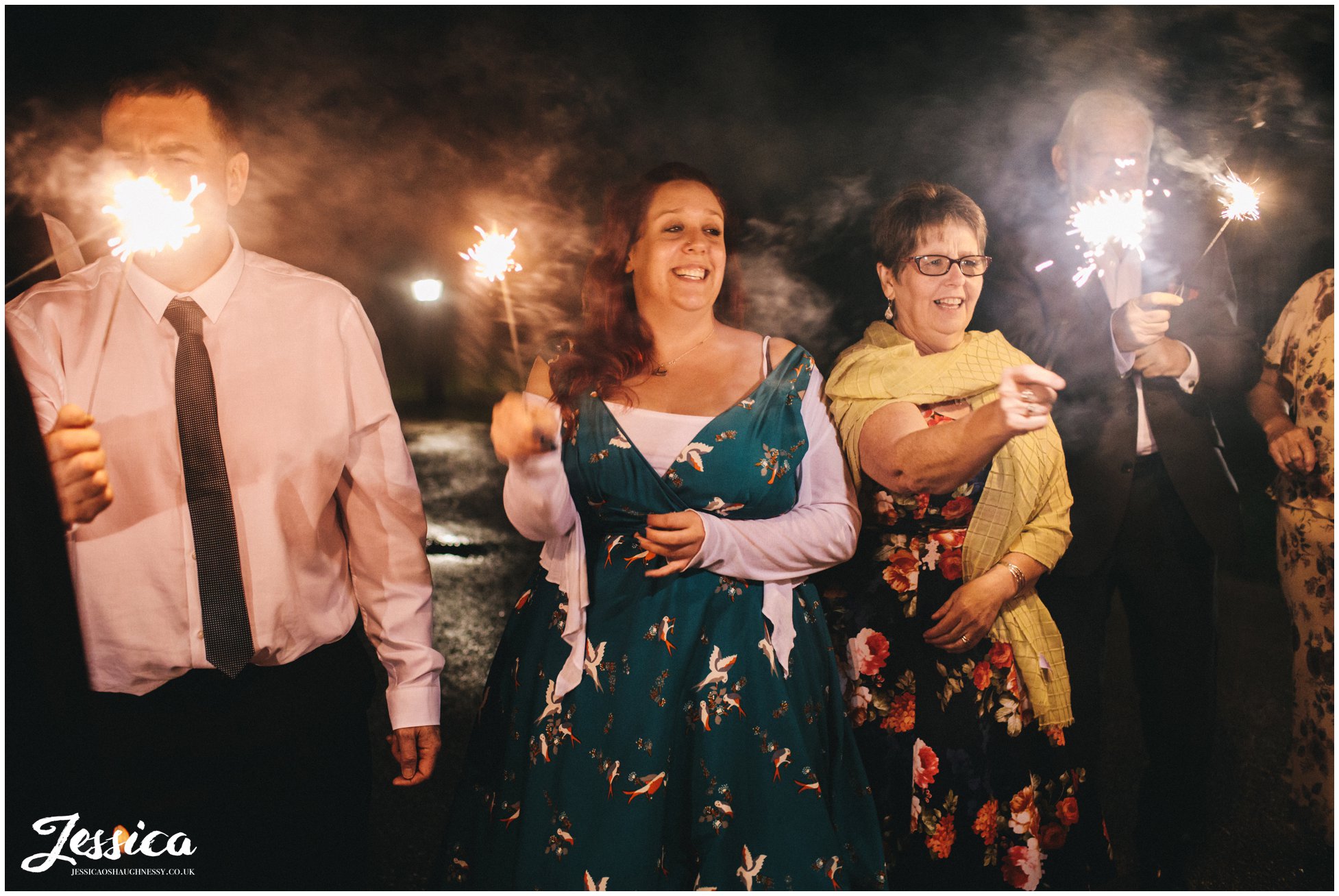 guests hold sparklers to light bride and groom
