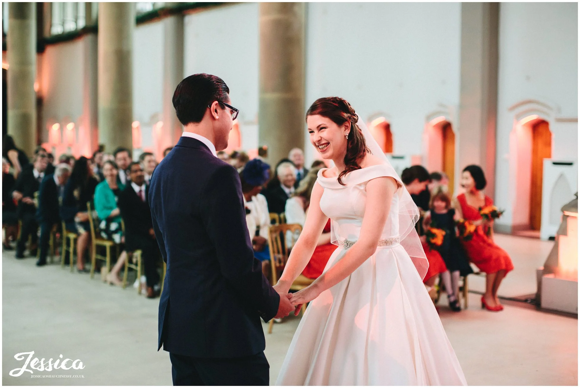 bride & groom hold hands laughing during their wedding ceremony