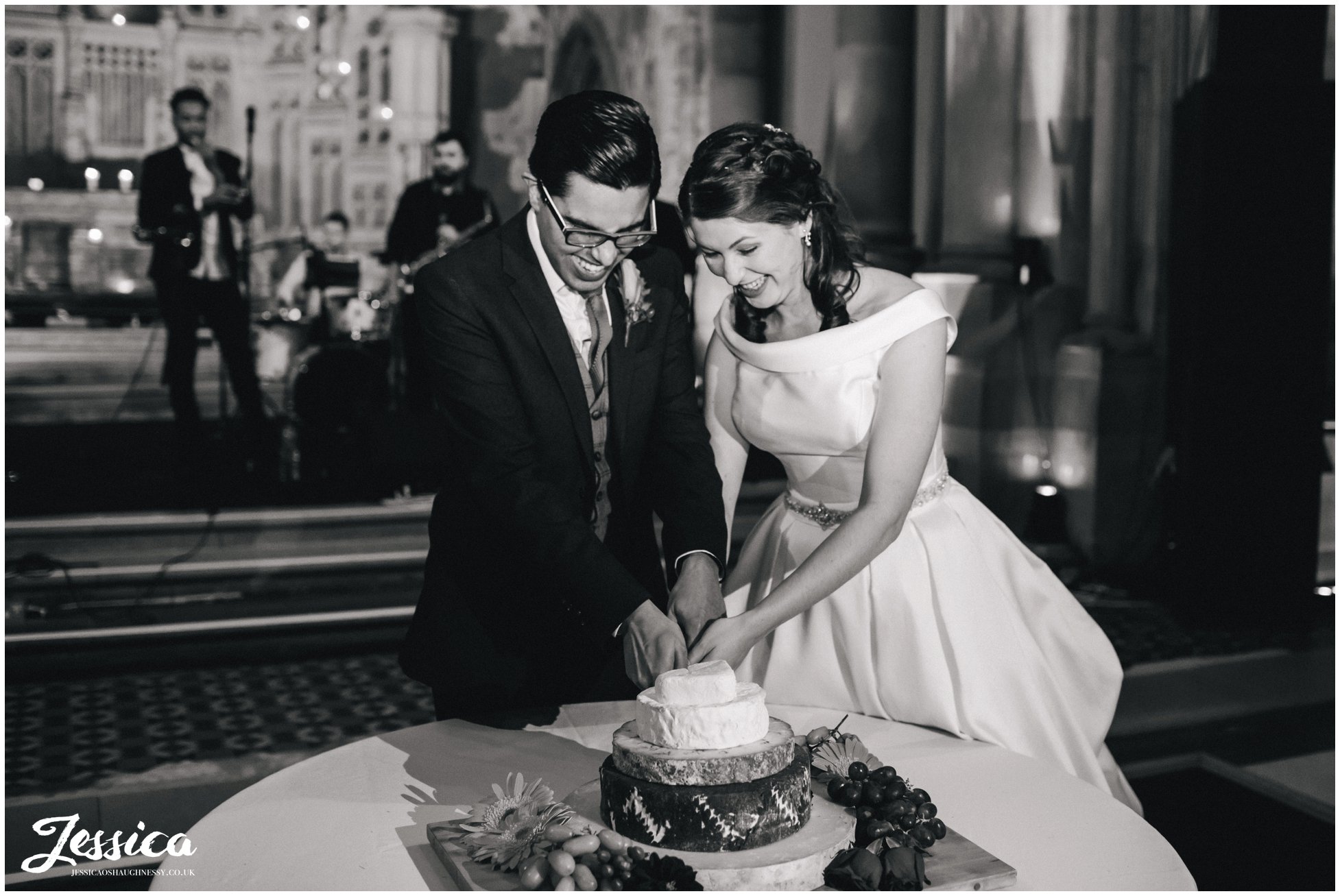 bride and groom cut wedding cake made from cheese