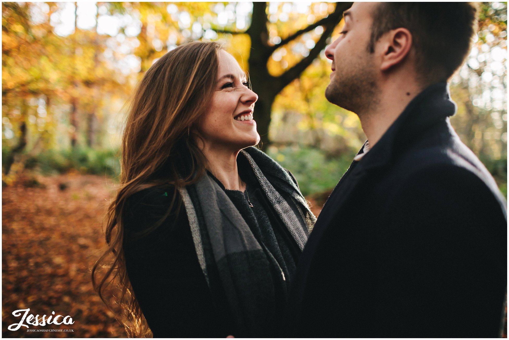 girl smiles at fiance during their forest engagement shoot