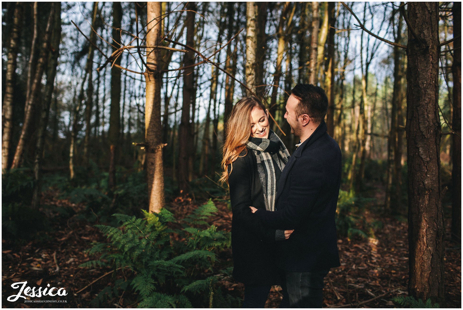 couple embrace in the trees at delamere forest in cheshire