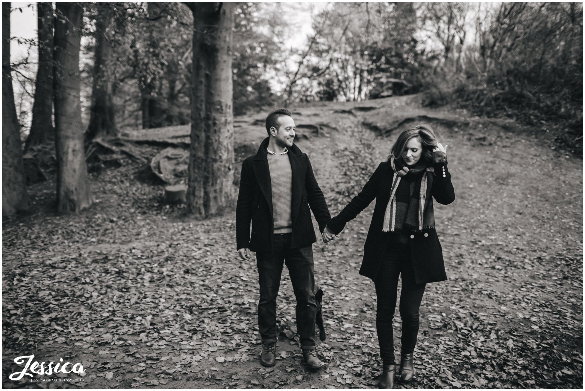 black and white photograph of couple walking through the woods