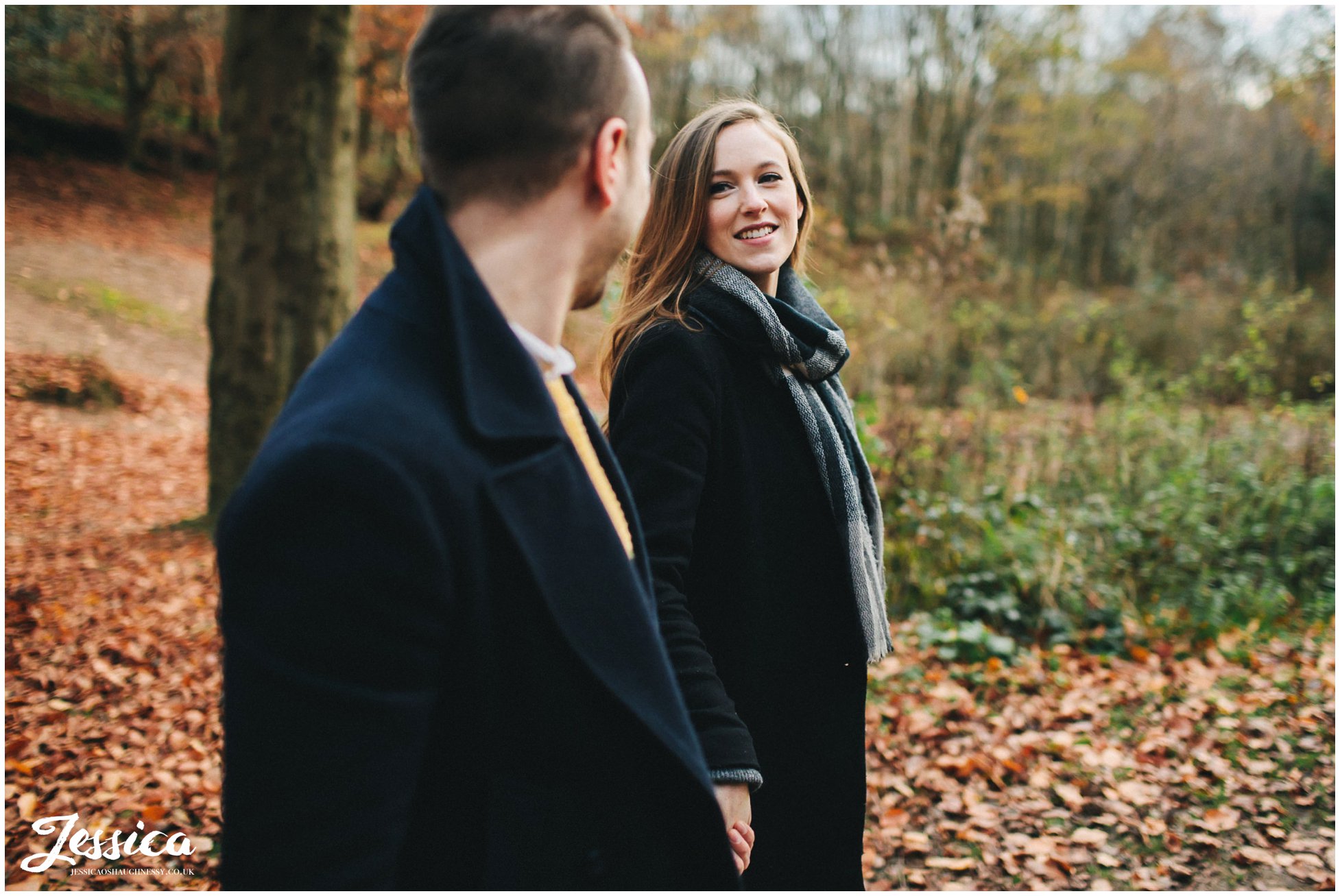 newly engaged couple hold hands walking through delamere forest in cheshire