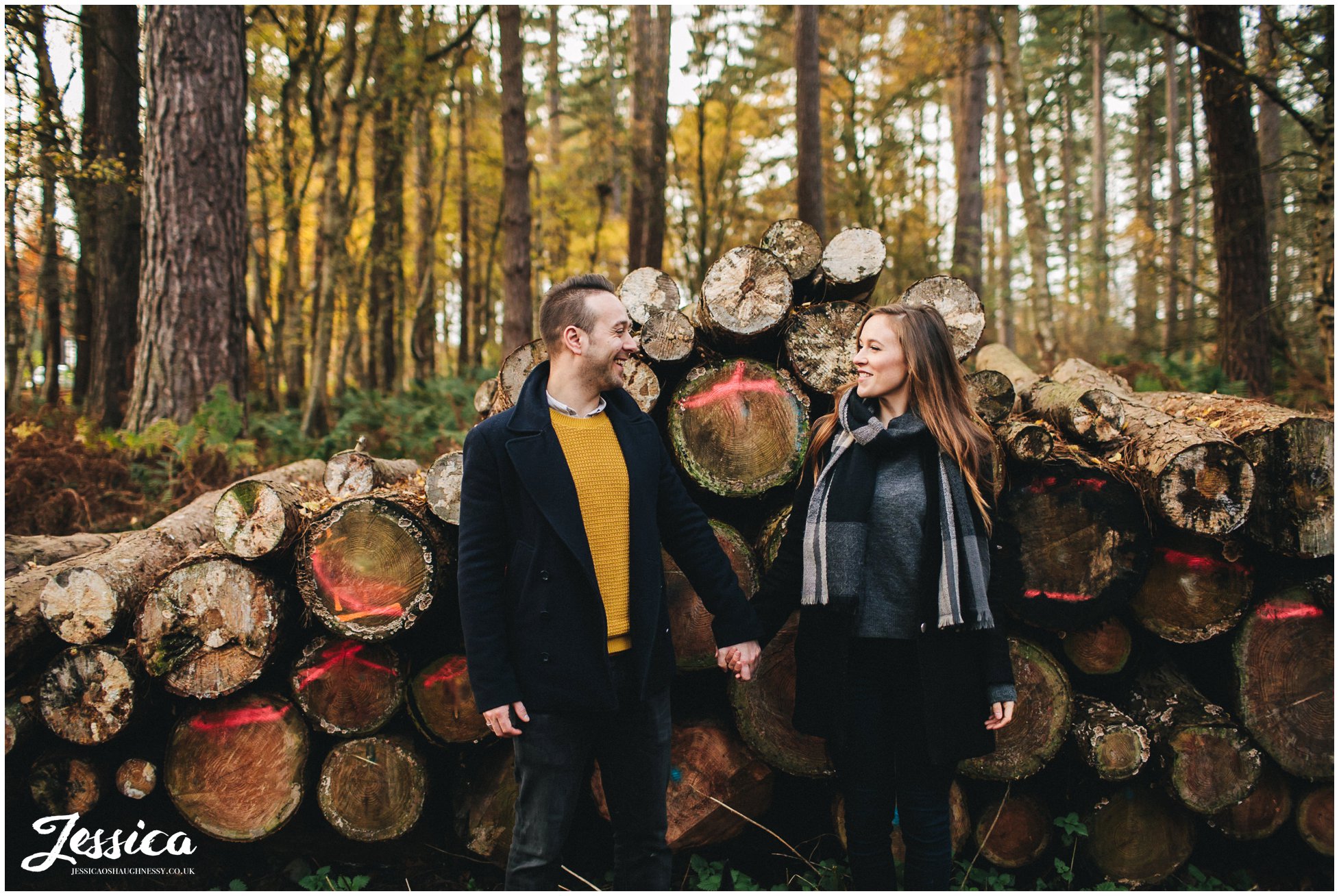 couple hold hands in front of cut logs, a cheshire engagement shoot