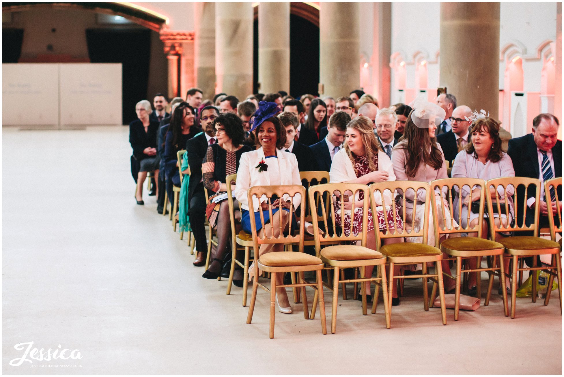 mother of the groom smiles proudly as her son waits for the bride