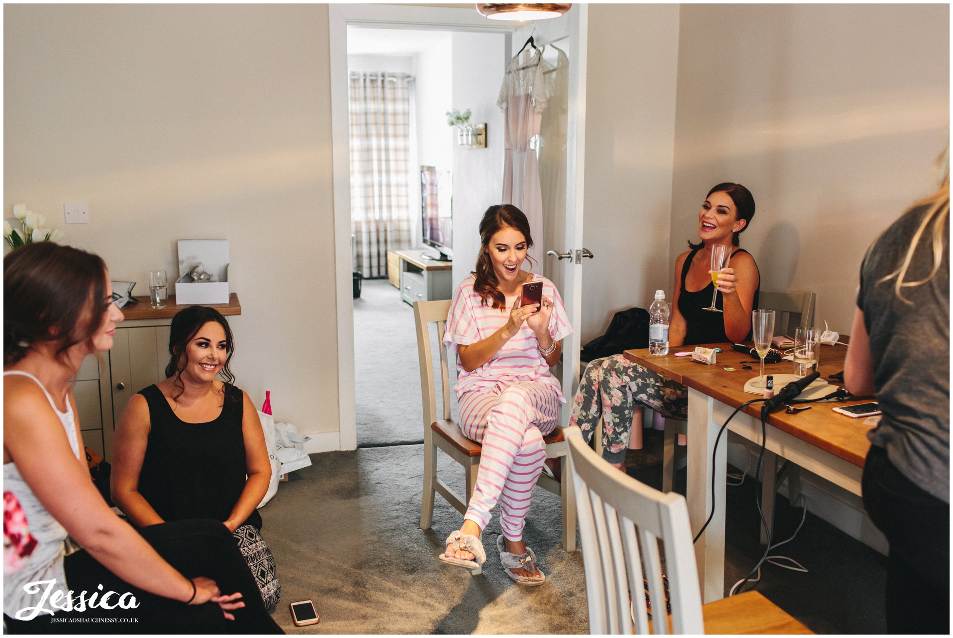 bridesmaids laugh together whilst getting ready for the wedding