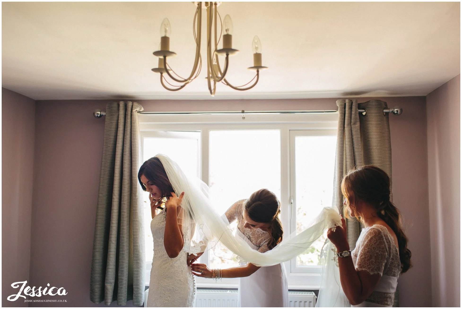 Bridesmaid help the bride into her wedding dress