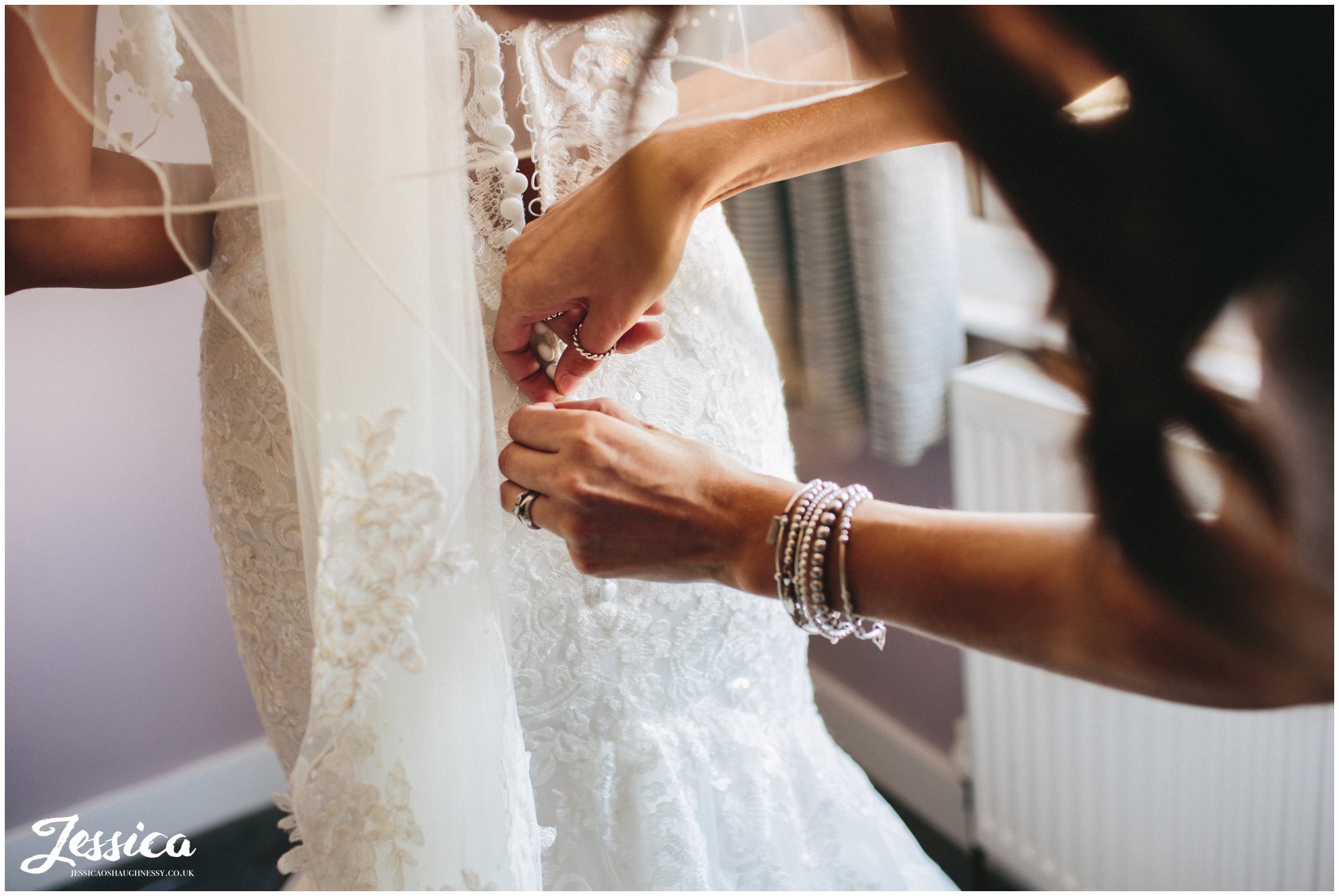 maid of honour fastens brides dress