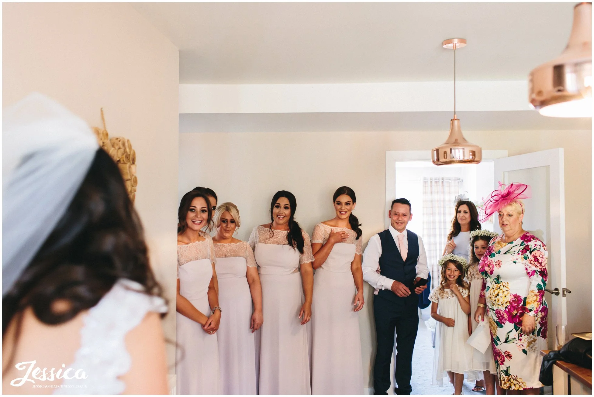 bride walks downstairs revealing her dress to friends & family