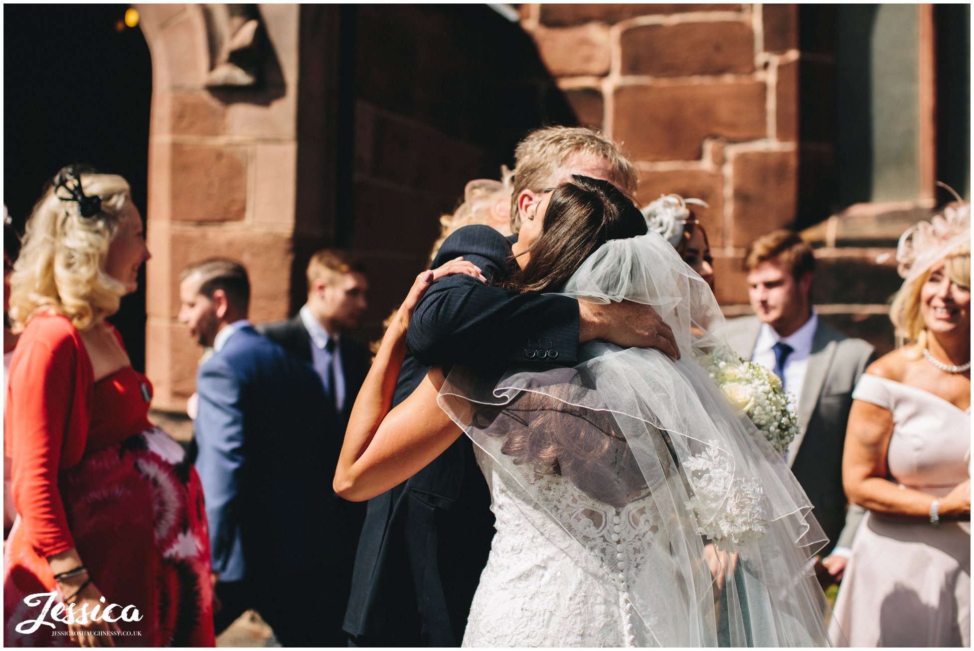 guest hugs the bride outside wirral chuch
